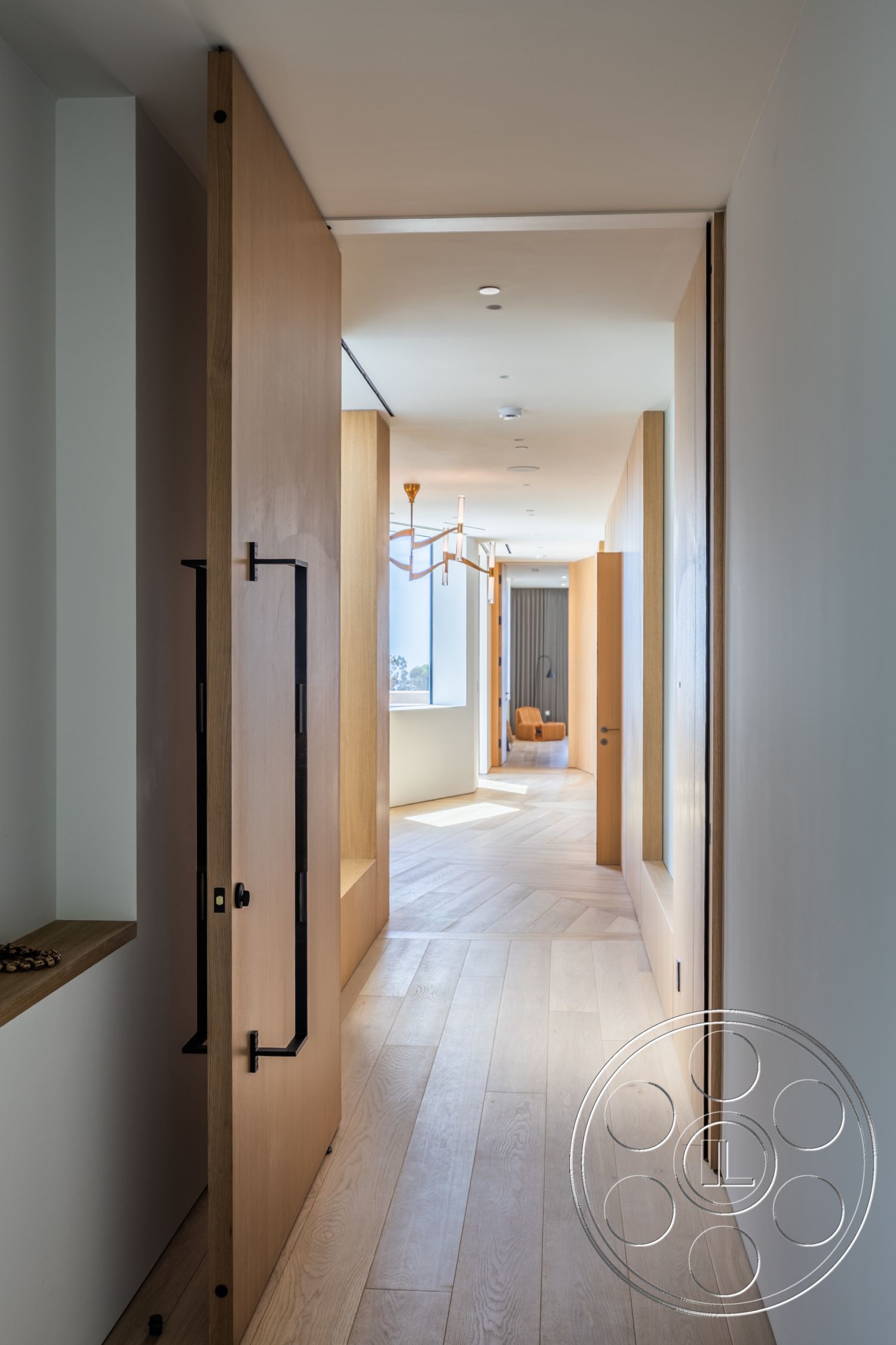 Modern 511 - neutral color palette, light hardwood flooring, floor-to-ceiling windows, modern architectural style, open space concept, contemporary lighting fixture, smooth wall finish, natural light exposure, exposed ceiling lights, interior hallway design, minimalist wooden doors, black metal door handle, wide corridor layout, integrated shelving unit, vertical wood paneling accents, large windows with scenic views