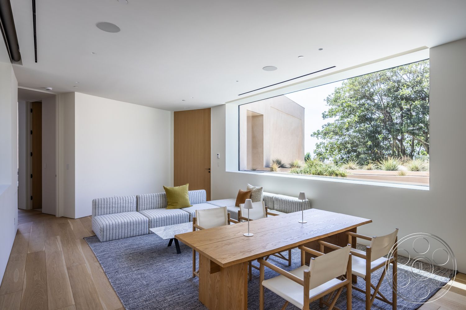 Modern 511 - light hardwood flooring, modern architectural style, open concept living space, large floor-to-ceiling windows, white plaster walls, sleek door design, natural light interior, neutral-toned area rug, clean lines and shapes, minimalist modern furniture, rectangular wooden dining table, striped fabric sofa, exterior landscaping view