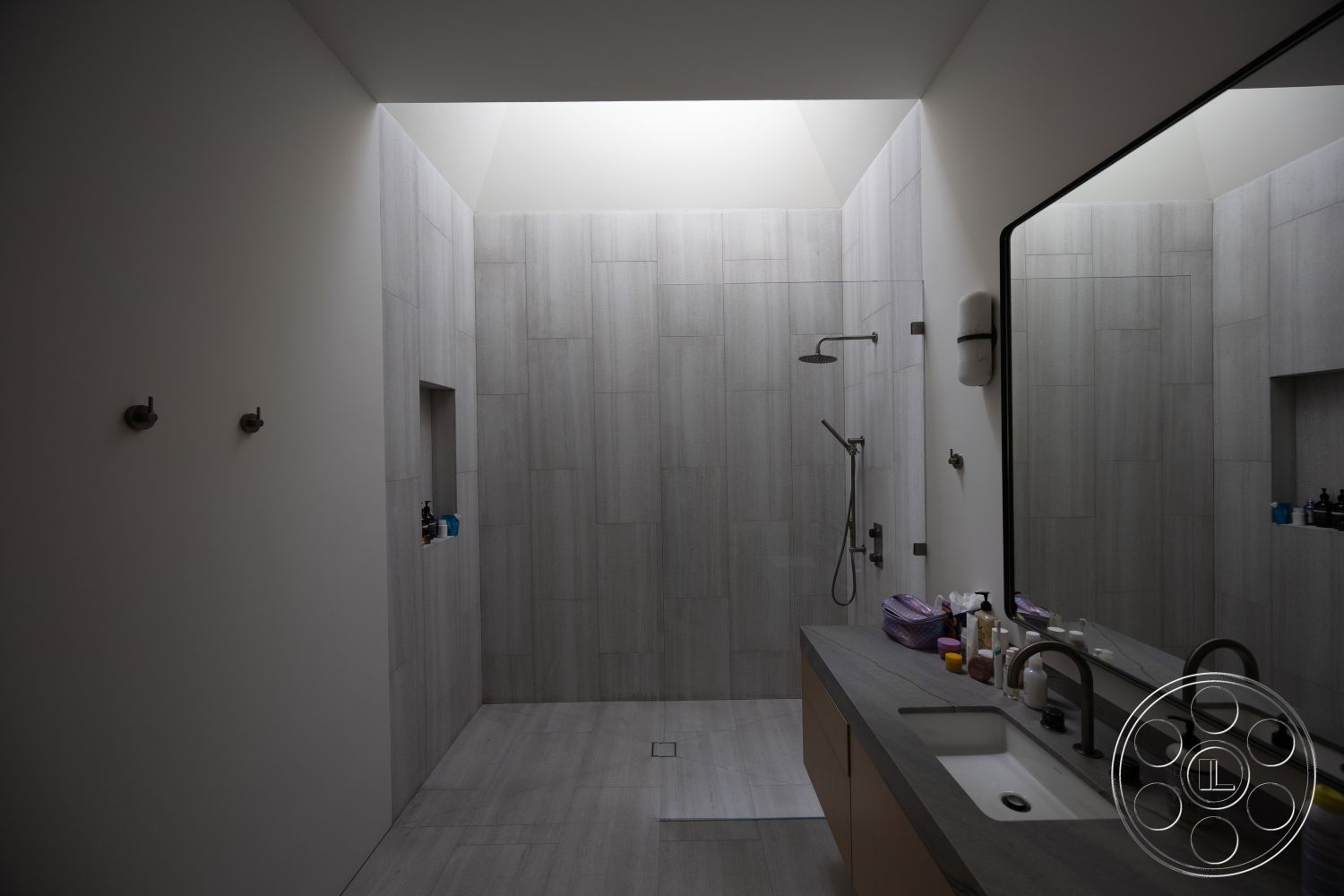 Modern 511 - neutral color palette, minimalist design, gray tile flooring, contemporary aesthetic, rain shower head, modern shower fixtures, interior bathroom, built-in shower niche, floating wooden vanity, frameless glass shower enclosure, large format gray tile shower walls, sloped ceiling with skylight, black faucet and hardware