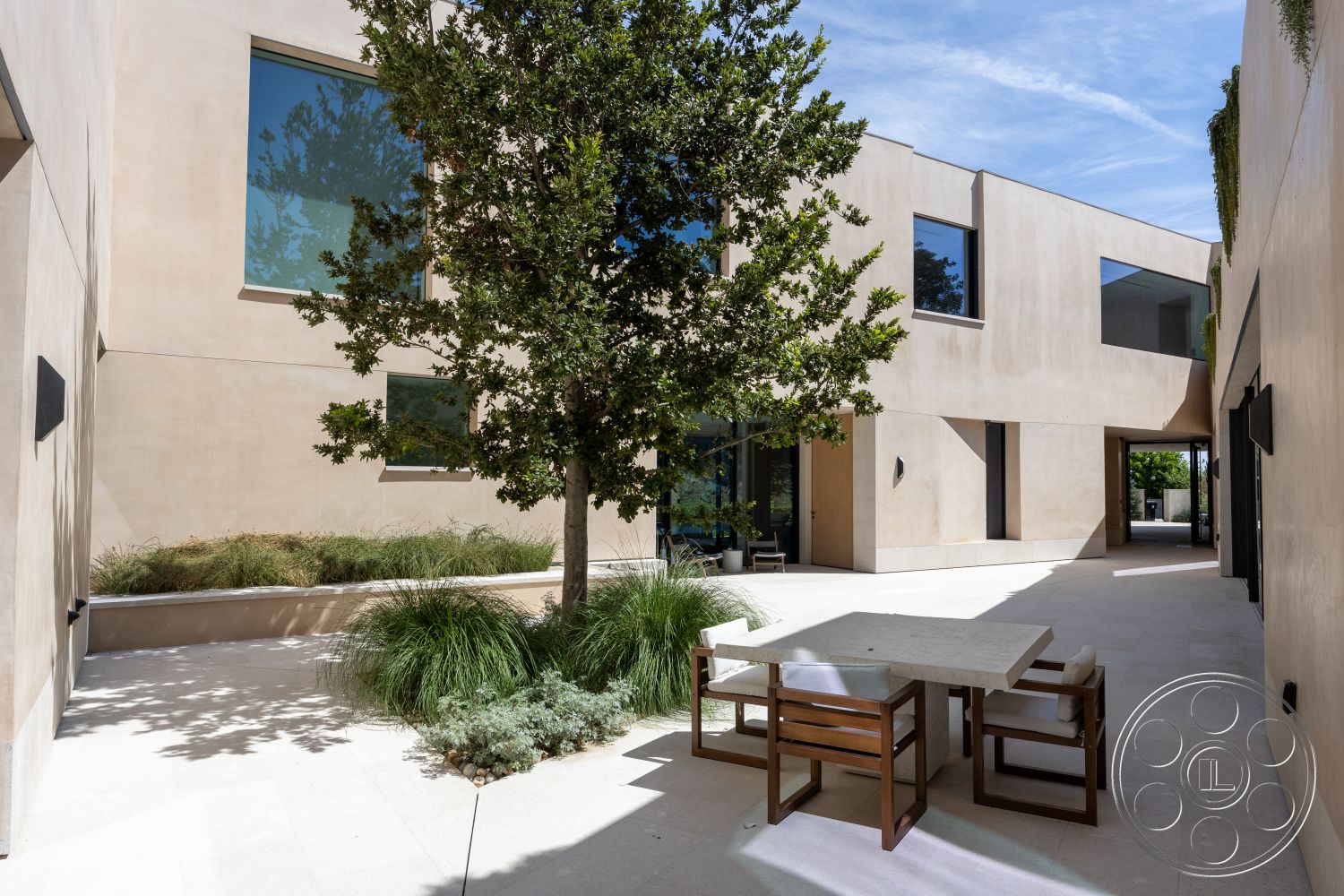 Modern 511 - large floor-to-ceiling windows, natural light-filled space, bright, airy atmosphere, interior courtyard with contemporary concrete walls, smooth plaster exterior finish, modern geometric architecture, minimalist outdoor dining set with stone tabletop, lush green landscaping with ornamental grass, rectangular patterned stone patio flooring, built-in planters with greenery, suburban residential setting