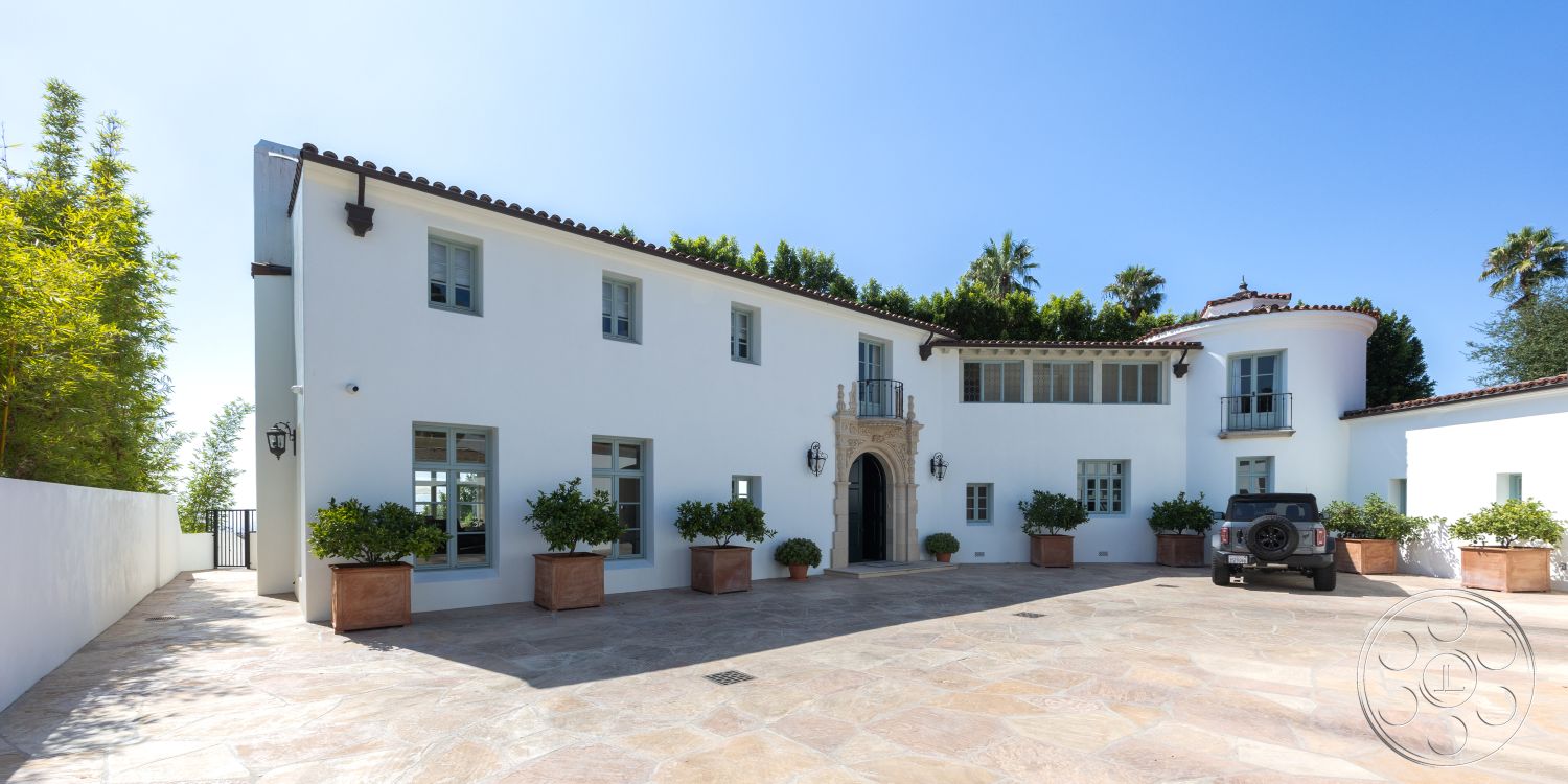 Spanish 168 - circular driveway, double-hung windows, balcony with wrought iron railing, exterior stucco walls, textured stucco finish, smooth concrete driveway surface, terra cotta tile roof, stone entryway arch, flagstone patio flooring, palatial front entrance, iron lantern light fixtures, tropical landscaping with palms, decorative window shutters, planter boxes with lush greenery, white painted exterior trim, arched doorways with stone accents, three-story home design, wall-mounted outdoor lighting, modern Mediterranean architectural style, serene suburban setting