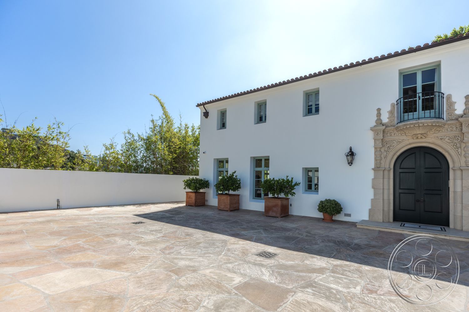 Spanish 168 - exterior, white stucco walls, classic architectural details, Mediterranean architectural style, balcony with wrought iron railing, landscaped garden area, natural stone patio flooring, private courtyard setting, arched stone entryway, black wooden front door, green window accents, planter boxes with greenery