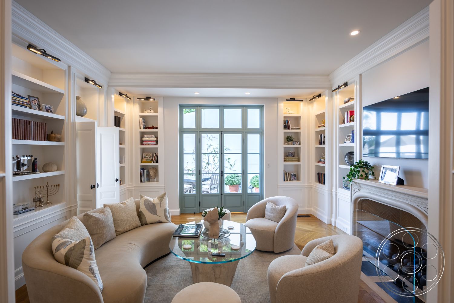 Spanish 168 - neutral color palette, glass coffee table, floor-to-ceiling windows, transitional style, cozy reading nook, decorative lighting fixtures, elegant architectural details, built-in bookshelves, hardwood living room floors, white painted walls, stone fireplace surround, crown molding details, rounded sofa with fabric upholstery, modern armchairs with plush cushions, glass door with multi-pane design, plant decor and natural light