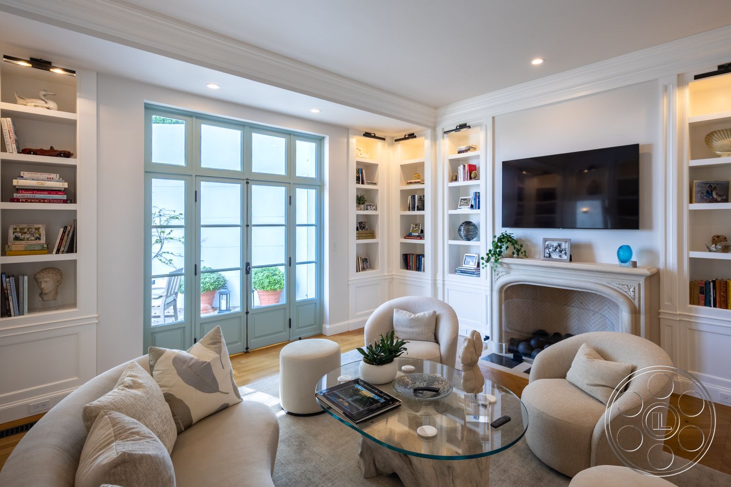 Spanish 168 - neutral color palette, contemporary decor, indoor plants, minimalist aesthetic, inviting atmosphere, open layout, glass coffee table, floor-to-ceiling windows, light wood accents, arched doorways, double French doors, stylish light fixtures, built-in bookshelves, exposed wood ceiling beams, hardwood living room floors, white painted walls, modern sectional sofa, stone fireplace surround, soft beige throw pillows