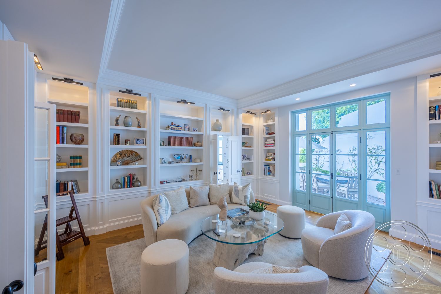 Spanish 168 - natural light, textured area rug, glass coffee table, minimalistic decor, white shiplap walls, cozy reading nook, contemporary architectural style, exposed wood ceiling beams, hardwood flooring in living room, open layout design, built-in bookshelves with LED lighting, curved furniture shapes, light-filled space with floor-to-ceiling windows, double French doors opening to garden patio, soft color palette with pastel accents