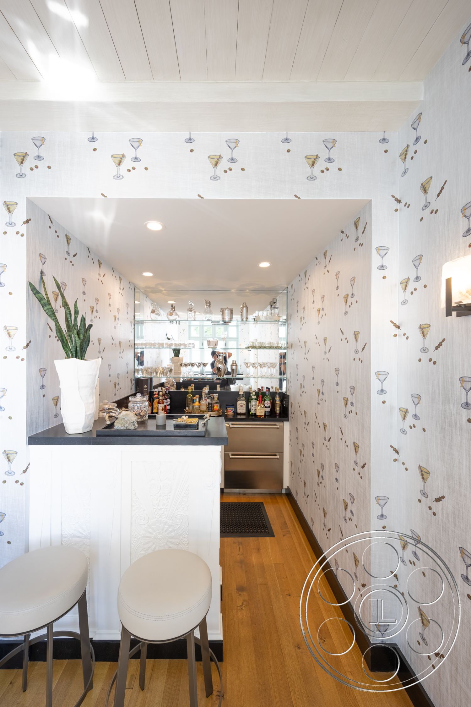 Spanish 168 - minimalist design elements, recessed lighting fixtures, contemporary bar area, white painted walls with cocktail print wallpaper, black granite bar countertop, white cabinetry with decorative accents, hardwood flooring in a warm tone, floor-to-ceiling mirror behind the bar, modern bar stools with round seats, interior home bar