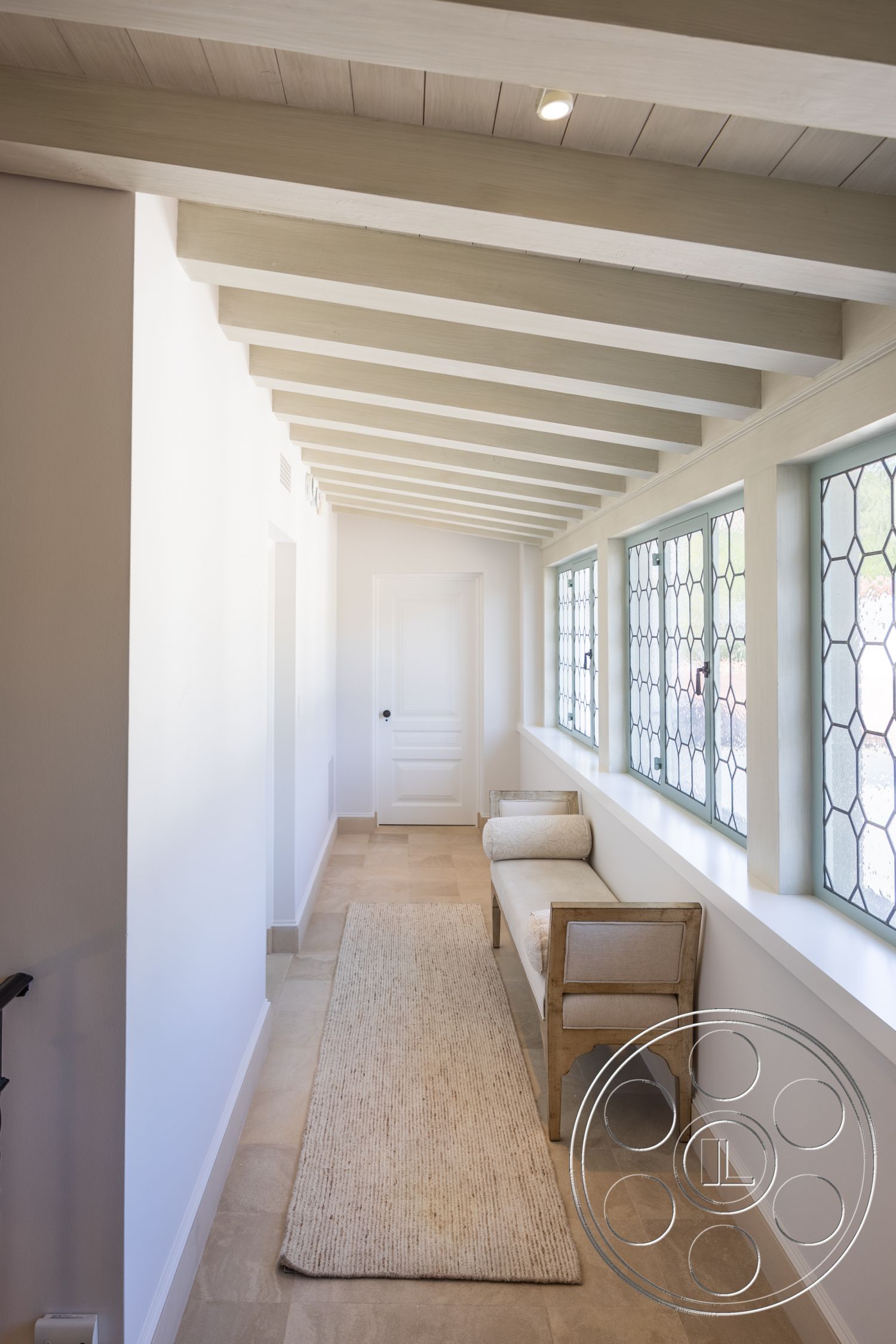 Spanish 168 - neutral color palette, cozy seating area, woven area rug, textured plaster walls, modern farmhouse style, interior hallway, minimalist interior design, wood beam ceiling, rectangular hallway layout, natural stone floor tiles, hexagonal window panes, natural light accent, light-colored wood accents, subtle contemporary decor