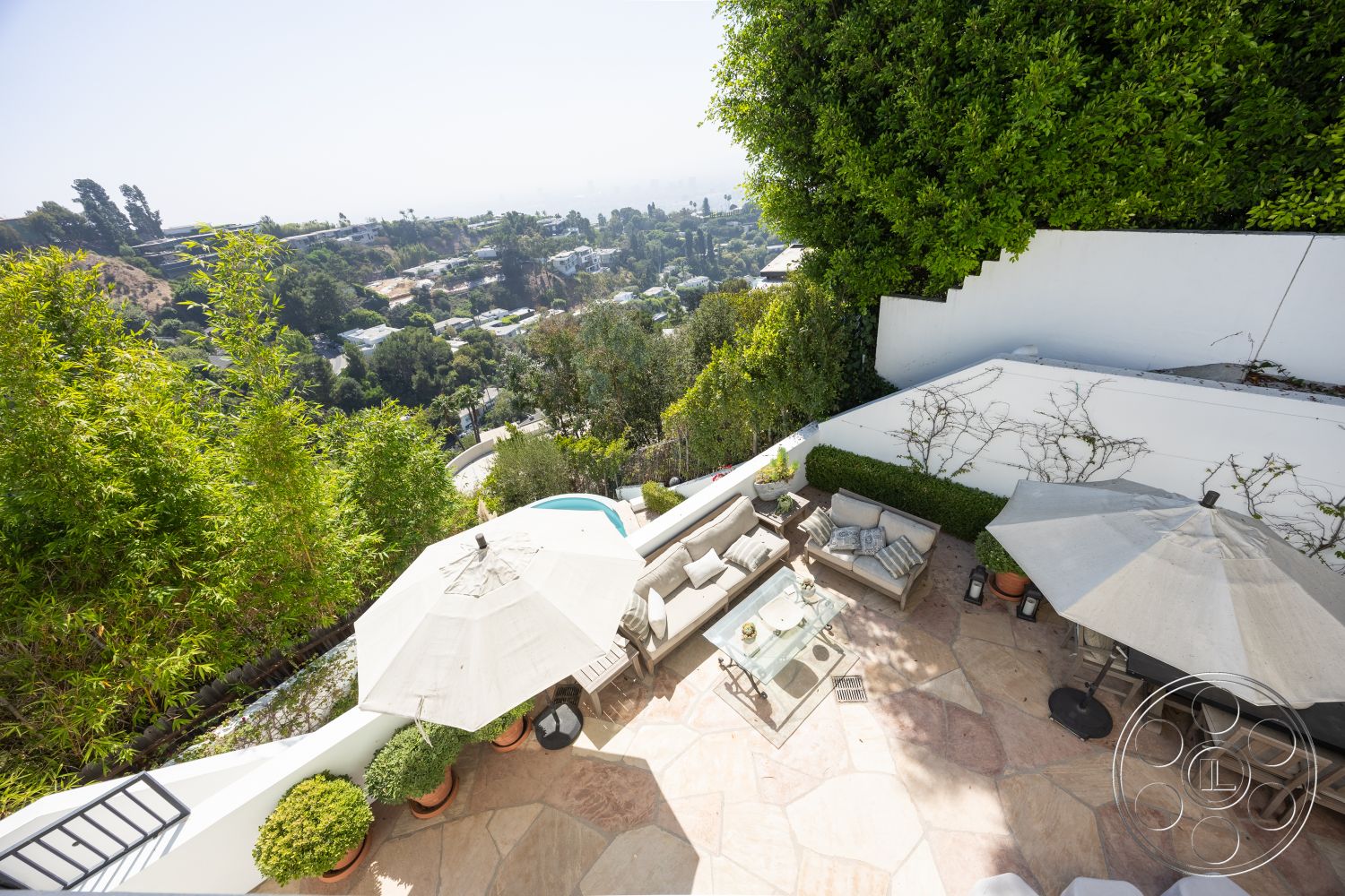 Spanish 168 - decorative potted plants, interior dining area, lush greenery landscaping, landscaped garden borders, urban hillside view, interior patio flooring, natural stone outdoor terrace flooring, concrete walls with white stucco finish, rectangular pool with waterfall feature, modern outdoor furniture set, umbrella shade structures, exterior built-in seating areas, open-air entertaining space, sectional outdoor couch, glass patio table centerpiece, natural light-drenched outdoor space