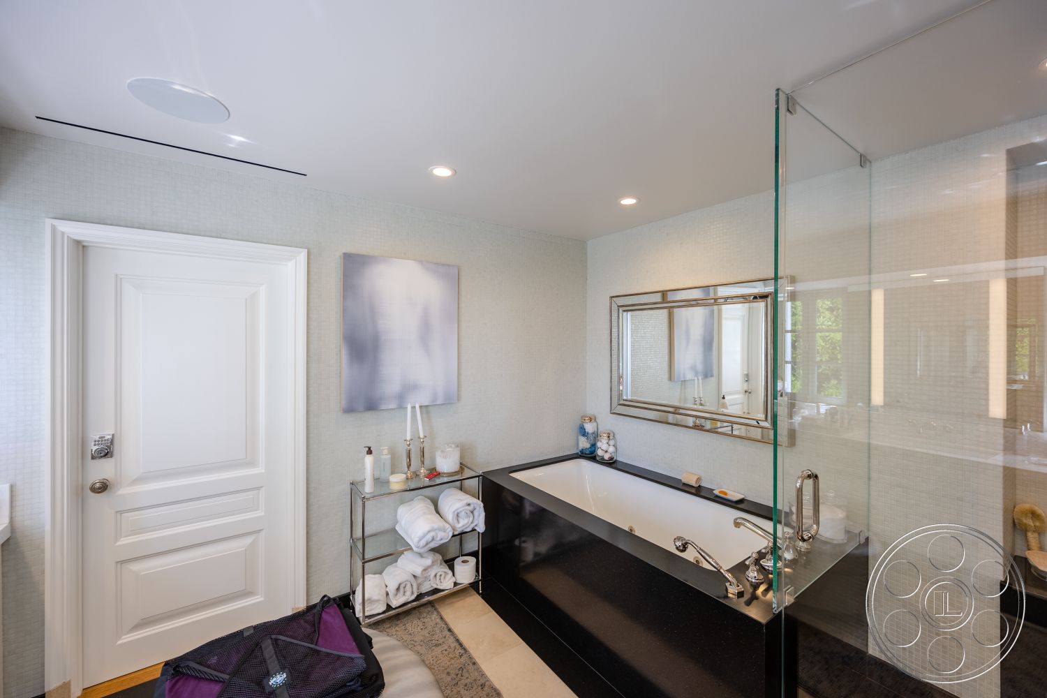 Spanish 168 - neutral color palette, glass shower enclosure, polished stone flooring, interior bathroom, white painted walls, modern recessed lighting, framed mirror above sink, luxurious spa-like atmosphere, chrome bathroom fixtures, textured tile bathroom walls, black countertop sink, rectangular freestanding bathtub, floating vanity with storage, exposed light switch, minimalist art decor, towel storage cart, soft towel arrangement