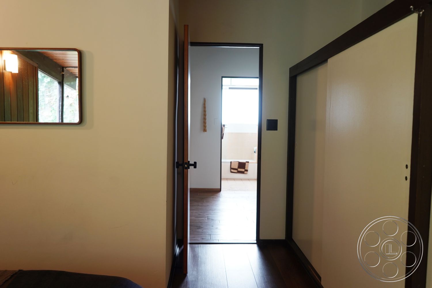 MCM 25 - interior neutral color palette, interior hardwood bedroom floors, interior natural light from large windows, interior recessed lighting fixtures, interior clean lines architecture, interior painted wall finish, interior sliding door to bathroom, interior modern minimalist mirror, interior wooden door frame, interior contemporary hallway design
