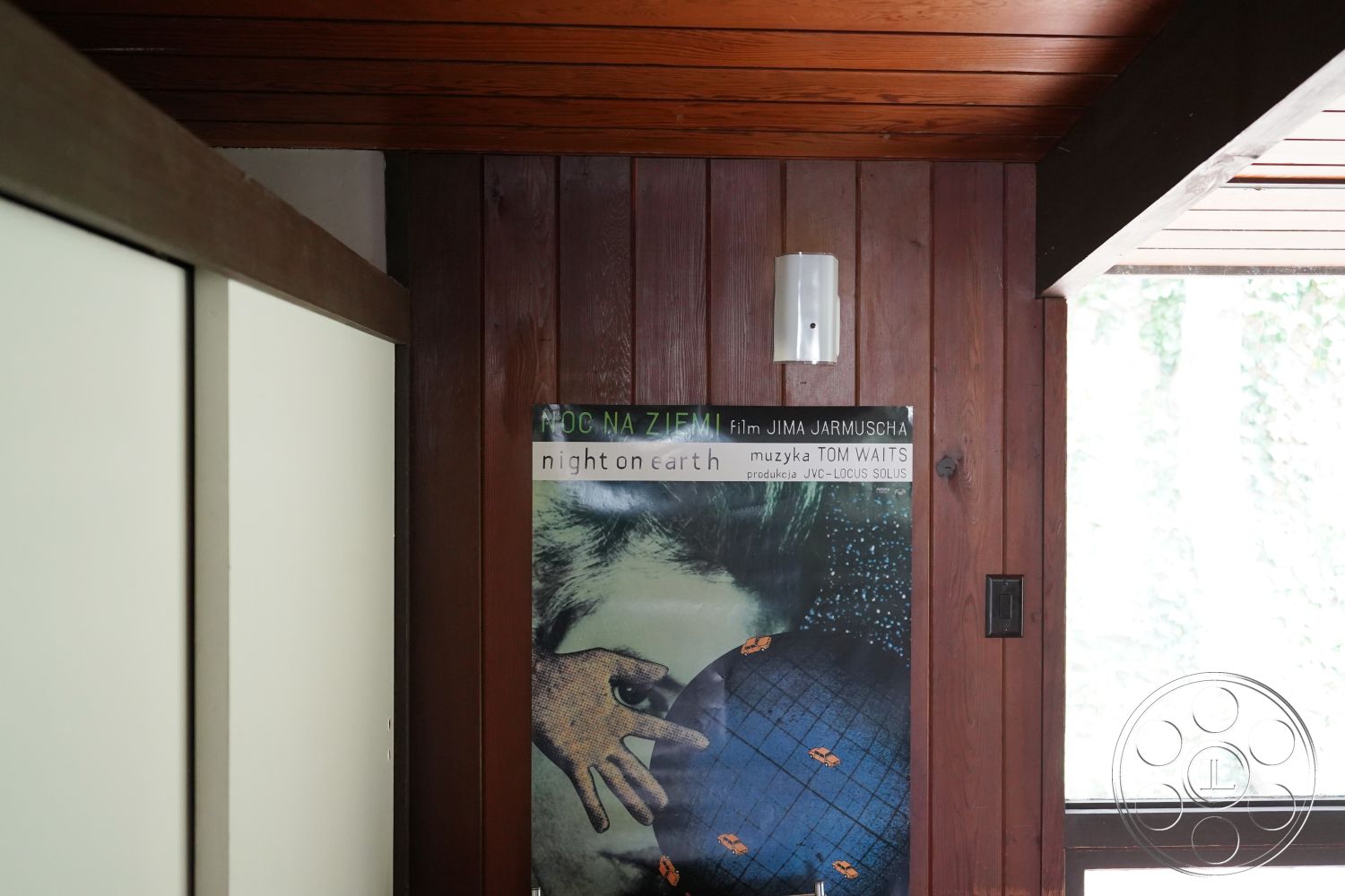 MCM 25 - interior space, modern light fixture, mid-century modern style, natural light sources, exposed wood paneling walls, horizontal wood slat ceiling, white painted closet doors, glass window with leafy view, art film poster decor