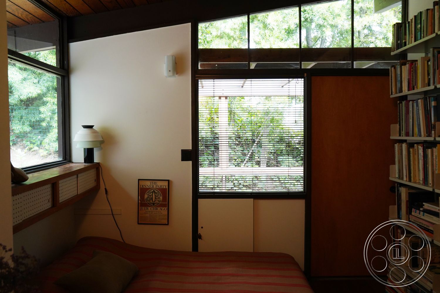 MCM 25 - natural light, minimalist design, open floor plan, multifunctional space, modern lighting fixtures, greenery view, floor-to-ceiling windows, cozy reading nook, contemporary interior, built-in bookshelves, sliding wood door, exposed wood ceiling beams, hardwood bedroom floors, white painted walls, horizontal wood panel accents, small bedroom, interior with outdoor connection, urban cabin style