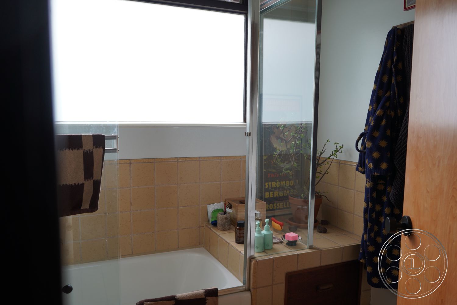 MCM 25 - natural light, minimalist aesthetic, glass shower enclosure, modern light fixtures, interior bathroom, potted plant accents, tile bathroom walls, wood cabinet storage, functional bathroom layout, textured yellow tile, vanity countertop, bathroom towel rack, framed art display, bathrobe hanging, sliding door for shower
