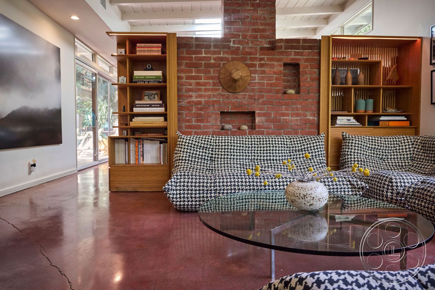 MCM 26 - open floor plan interior, cozy seating area interior, exposed brick accent wall interior, natural light from large windows interior, minimalist decor interior, glass coffee table interior, polished concrete living room flooring interior, wooden bookshelf unit interior, hounds-tooth patterned upholstery interior, vaulted ceiling with wood beams interior, built-in book shelves interior, rustic decorative elements interior, modern art pieces interior, earthy color palette interior