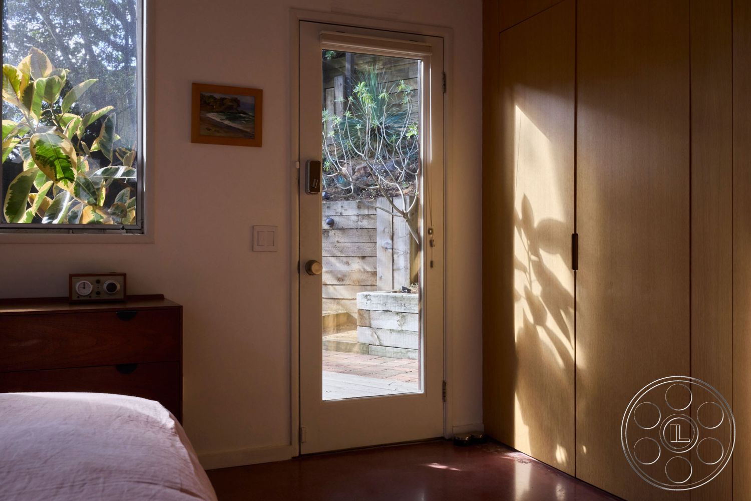 MCM 26 - interior framed artwork on wall, interior minimalistic design, interior rectangular window, interior wood paneling closet, interior wood nightstand, interior glass door with natural light, interior smooth concrete flooring, interior situated in a garden setting, interior soft lighting, interior plant view from window, interior bedroom with natural elements