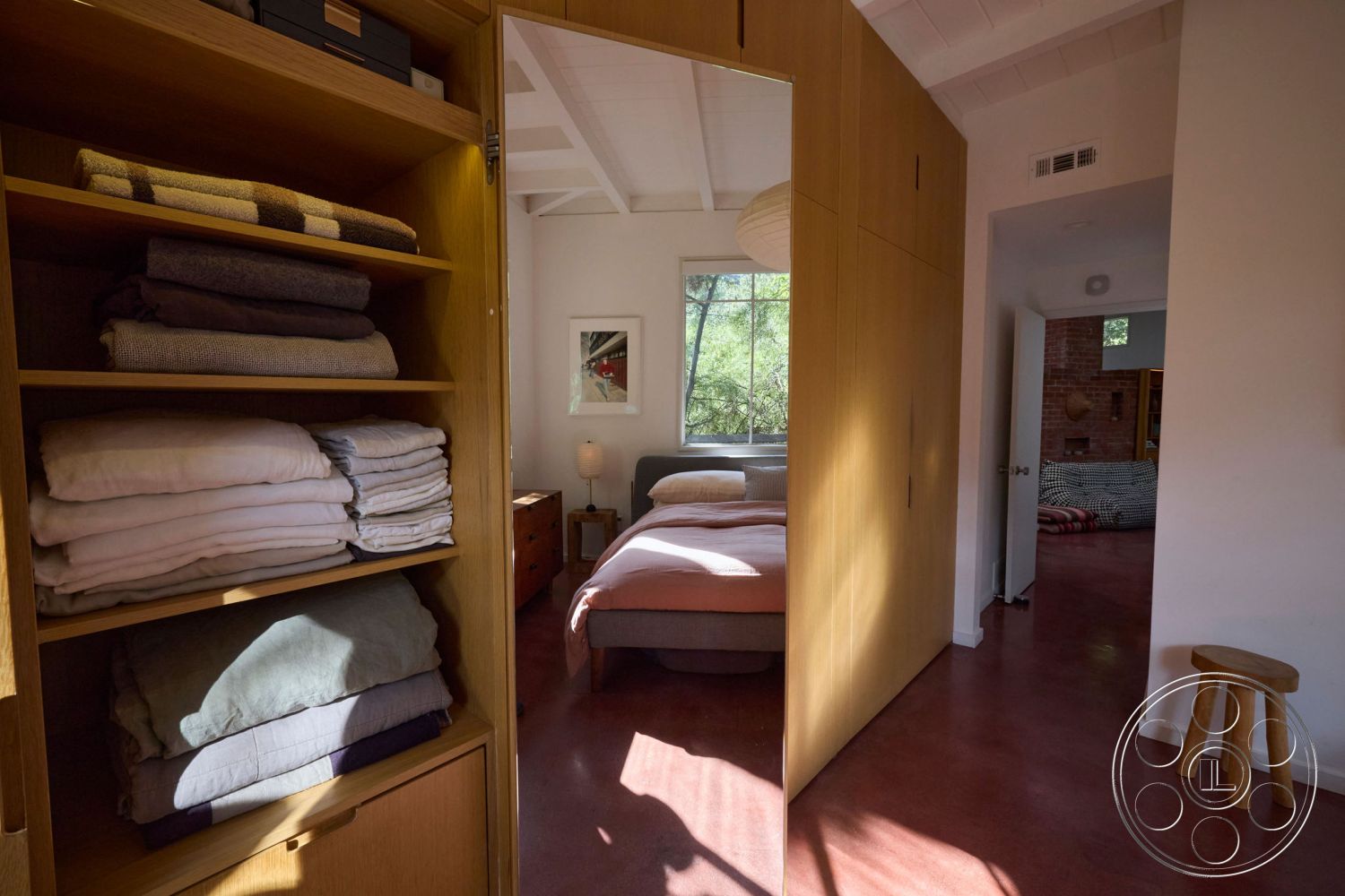 MCM 26 - interior vaulted ceiling, interior natural light, interior cozy atmosphere, interior floor-to-ceiling windows, interior contemporary decor, interior natural wood accents, interior warm color palette, interior wooden paneling, interior modern furniture, interior seamless indoor-outdoor flow, interior wood storage shelves, interior stacked linens, interior terracotta concrete floors, interior minimalistic bedroom, interior light fixtures, interior accent wall with art, interior multifunctional space