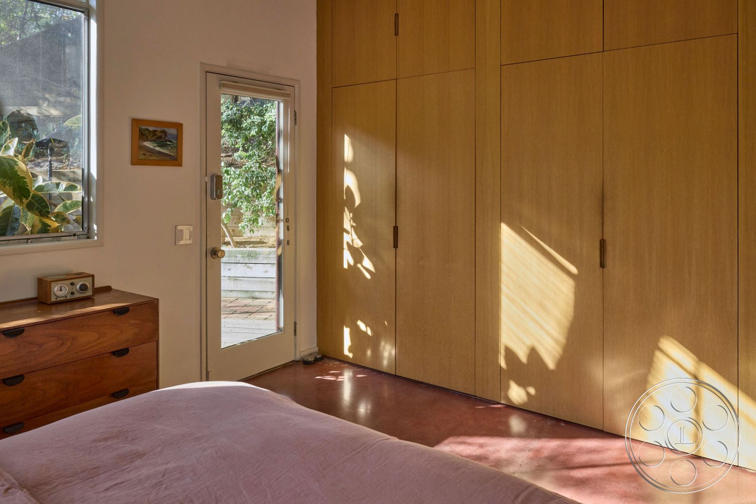 MCM 26 - neutral color palette, minimalist design, open layout, natural wood cabinetry, polished concrete flooring, modern decor elements, outdoor access, textured wall finish, sliding glass door, soft natural light, contemporary aesthetic, interior bedroom, large window with garden view, solid wood dresser, floating cabinet, smooth cabinetry handles