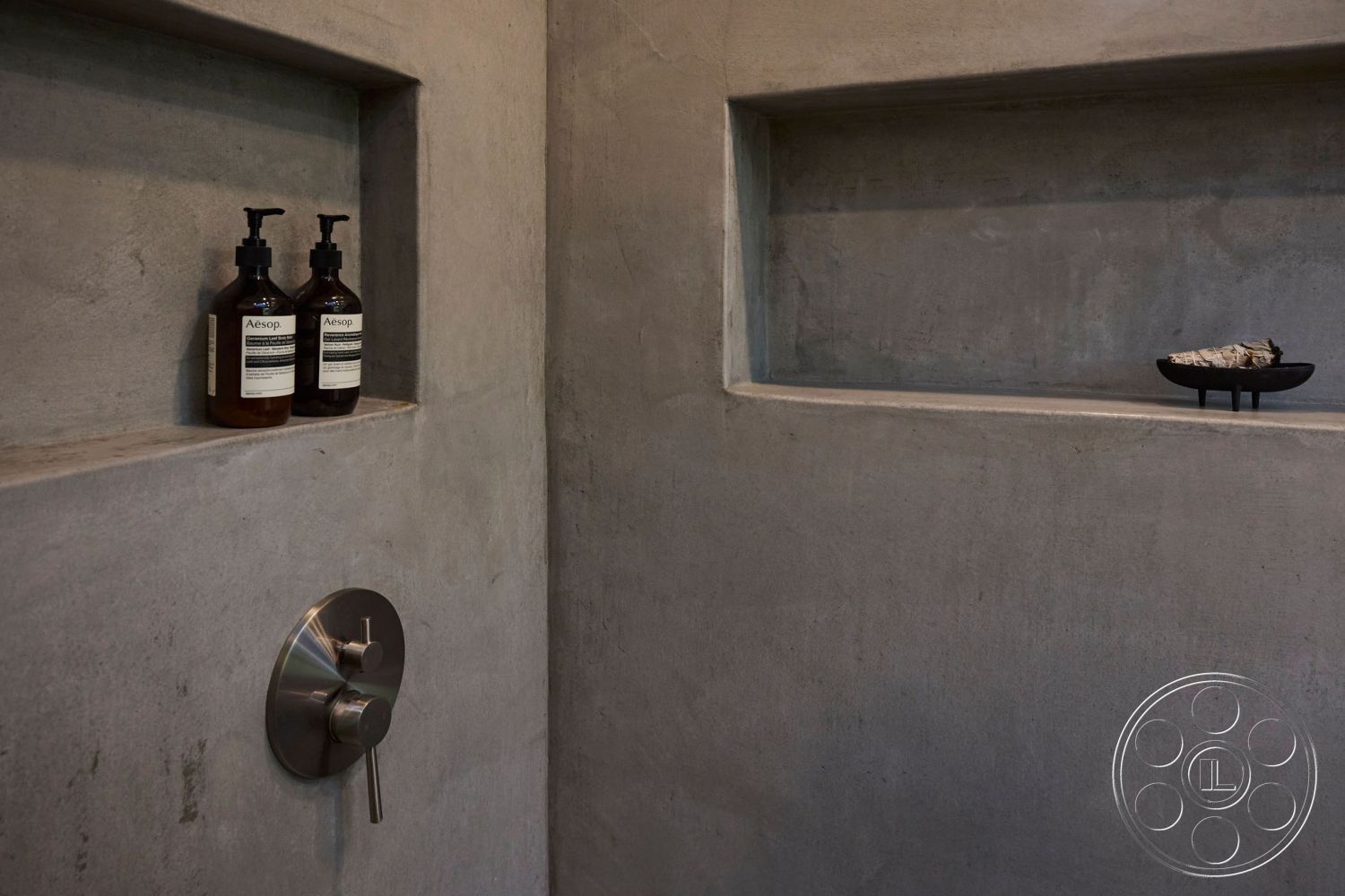 MCM 26 - smooth concrete flooring, textured plaster walls, minimalist bathroom design, modern industrial style, interior spa-like atmosphere, exposed concrete shower walls, stainless steel shower fixture, concrete niche shelves, ambient lighting elements, functional niche for toiletries