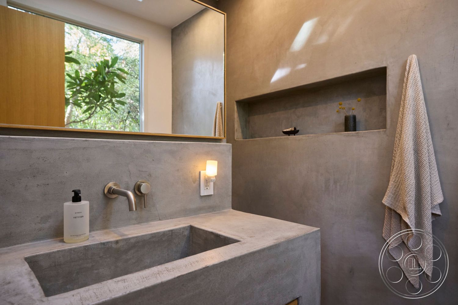 MCM 26 - interior textured plaster wall, interior natural light, interior minimalistic design, interior soft ambient lighting, interior zen-inspired decor, interior concrete countertop, interior concrete walls, interior concrete sink, interior recessed shelving, interior modern faucet, interior wall-mounted towel holder, interior warm wood door, interior sleek mirror, interior botanical view, interior organized storage