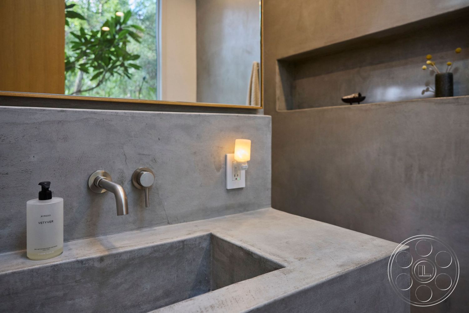 MCM 26 - interior natural light from windows, interior minimalistic design, interior built-in shelving, interior modern aesthetic, interior spa-like atmosphere, interior modern bathroom, interior accent lighting, interior concrete sink countertop, interior contemporary style, interior polished concrete walls, interior stainless steel faucet fixtures, interior wood door frame, interior sleek bathroom design