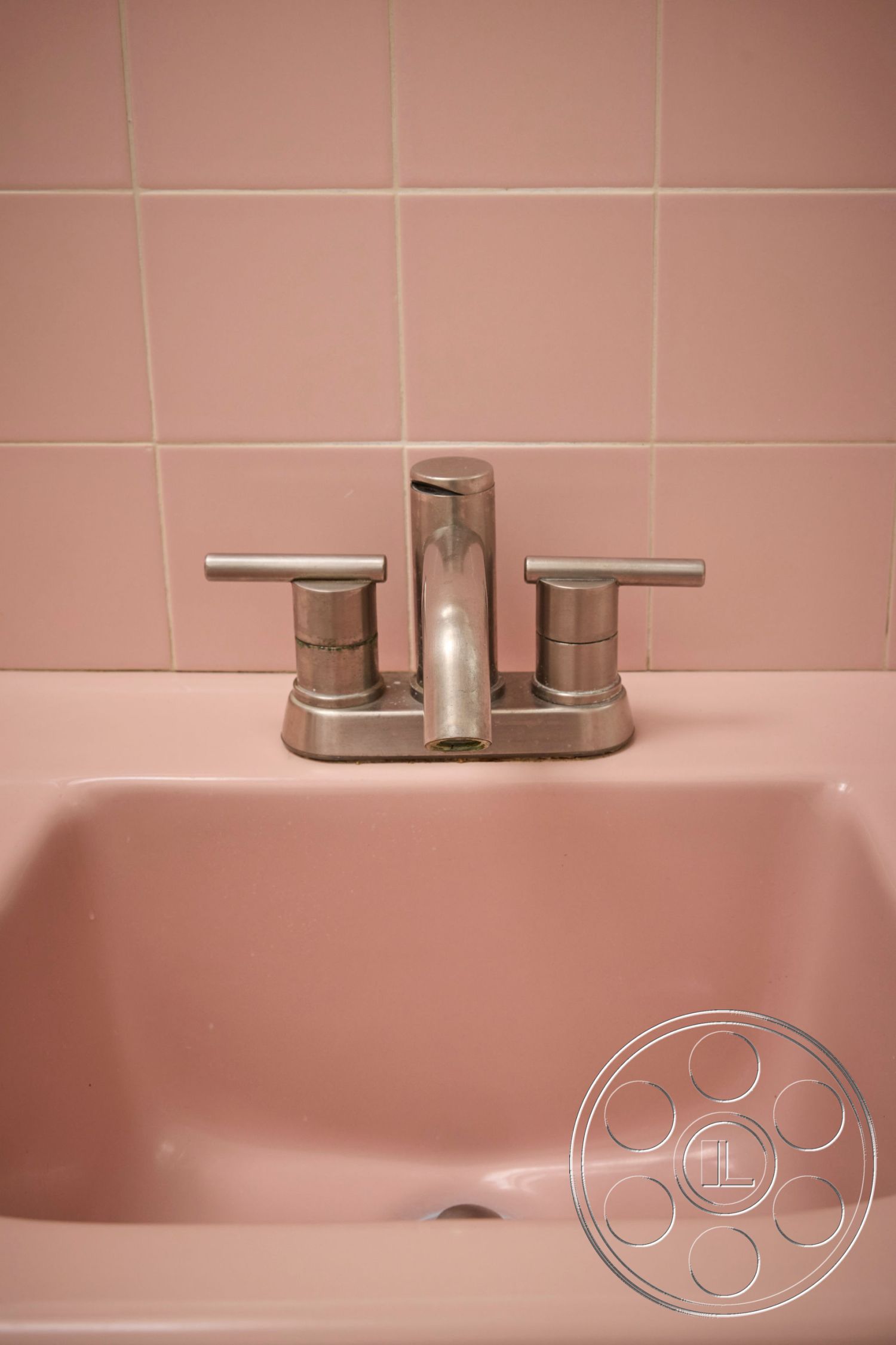 MCM 26 - minimalist design, sleek faucet design, modern bathroom fixtures, interior bathroom setting, white tiled bathroom walls, stainless steel faucet, pink ceramic sink, retro bathroom style