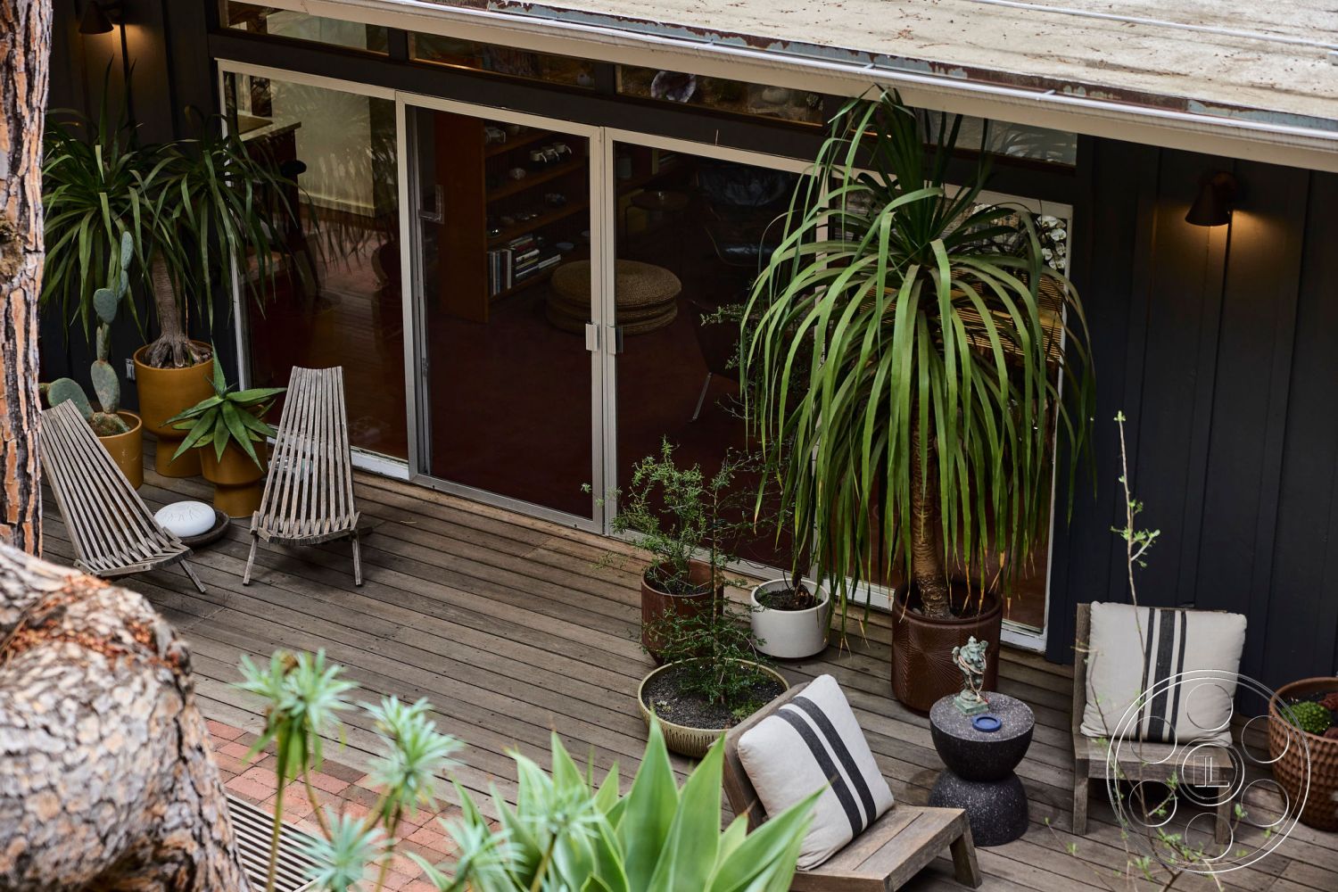 MCM 26 - glass sliding doors, sustainable materials, contemporary design elements, modern outdoor seating area, wood deck patio flooring, potted tropical plants, slatted wood lounge chairs, dark wood exterior walls, desirable urban setting, interior living room view