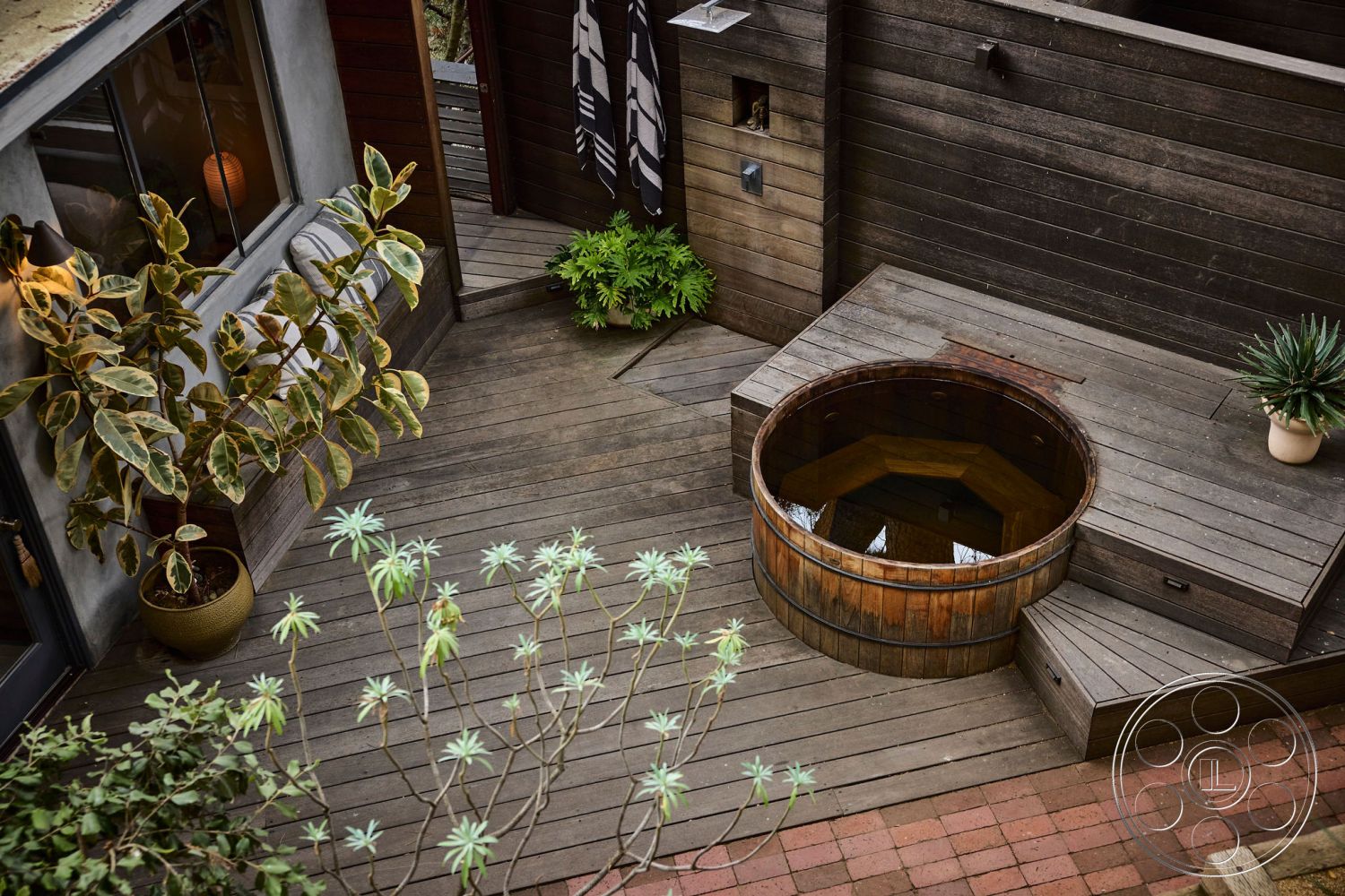 MCM 26 - outdoor living space, contemporary outdoor space, modern minimalist design, exterior wood deck flooring, rectangular patio layout, stone garden pathway, landscaped garden with potted plants, wood barrel hot tub, textured wood wall paneling, hexagonal hot tub shape, steps leading to hot tub, planted succulent garden, private outdoor relaxation area, cedar wood accents, natural wood aesthetic