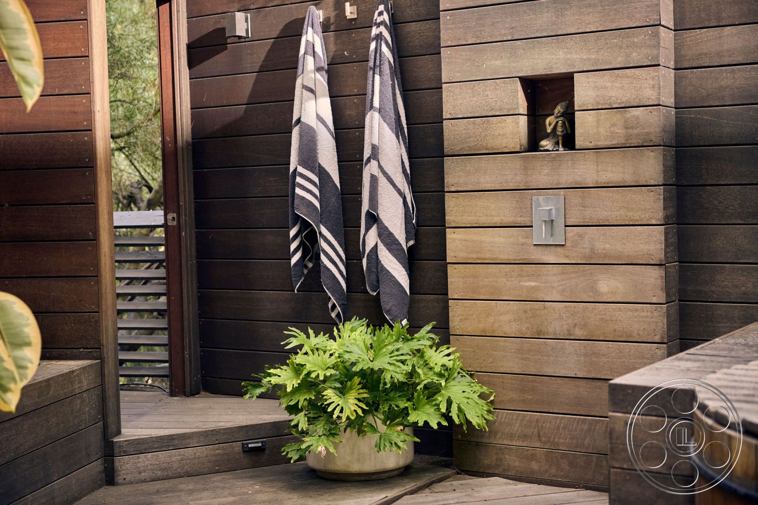 MCM 26 - natural wood decking, horizontal wood paneling, minimalist outdoor space, lush greenery surrounding, sunlit garden setting, exterior wood slat wall, modern outdoor shower area, textured wood plant pots, outdoor towel hooks, nook with wood accent, decorative stone feature, relaxed contemporary design