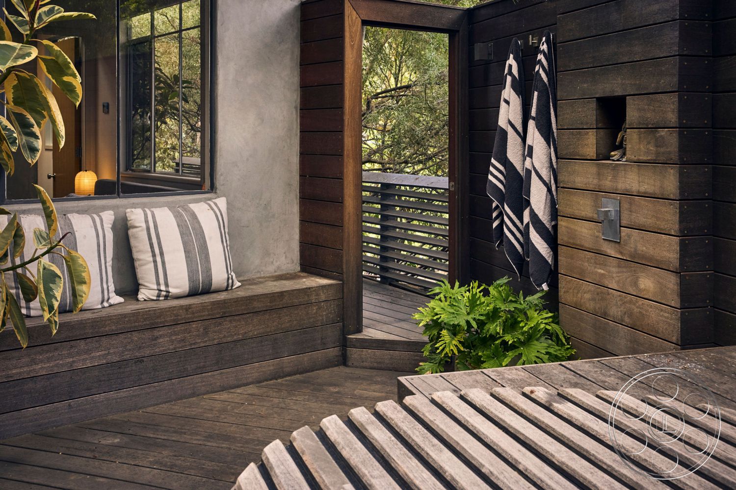 MCM 26 - sliding glass door, rustic design elements, cozy reading nook, wooden deck flooring, textured plaster wall, modern minimalist aesthetic, green foliage accents, modern outdoor seating area, shiplap wall treatment, wooden bench seat with cushions, black and white stripped towels, natural light with large window, organic indoor plants