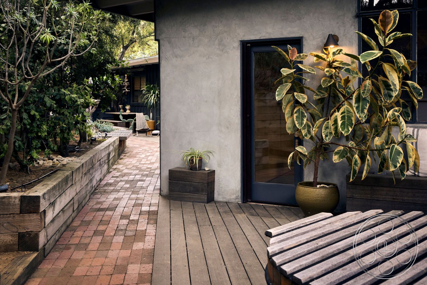 MCM 26 - exterior wood deck flooring, exterior landscaped garden setting, exterior concrete walls, exterior glass door, exterior red brick pathway, exterior planter with foliage, exterior natural stone retaining wall, exterior wooden seating area, exterior contemporary home design, exterior shaded outdoor space