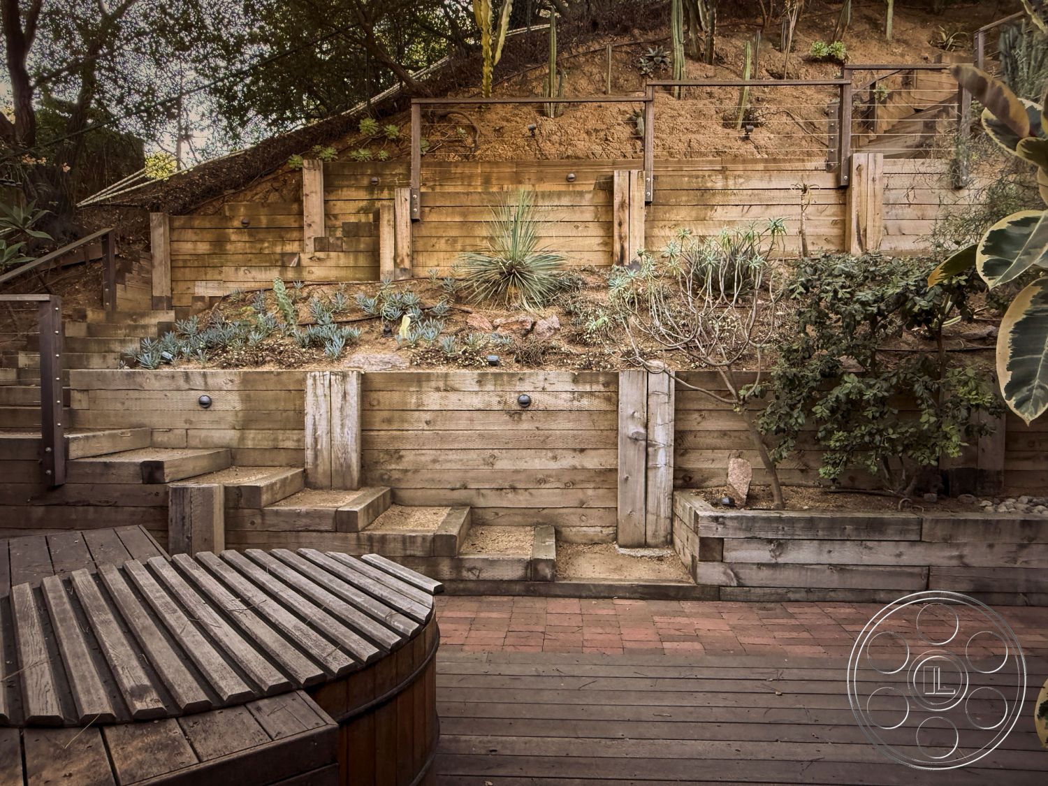 MCM 26 - exterior wooden pathway, exterior wooden deck flooring, exterior metal railing, exterior wood retaining wall, exterior multi-level wooden steps, exterior circular wooden hot tub, exterior landscaped garden bed, exterior stone aggregate planters, exterior drought-resistant plants, exterior hillside setting, exterior rustic design elements, exterior natural materials integration, exterior warm wood tones, exterior textured landscaping, exterior serene outdoor environment