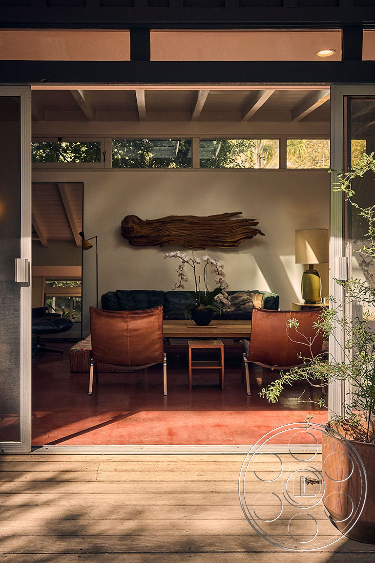 MCM 26 - contemporary furniture, minimalist design elements, modern coffee table, seamless indoor-outdoor transition, floor-to-ceiling windows, warm ambient lighting, comfortable seating area, indoor plant decor, lush garden view, interior hardwood flooring, exposed wooden ceiling beams, open floor plan living space, textured wall art feature, leather lounge chairs, earthy tone color palette, natural light accentuated space, rustic wood grain accents