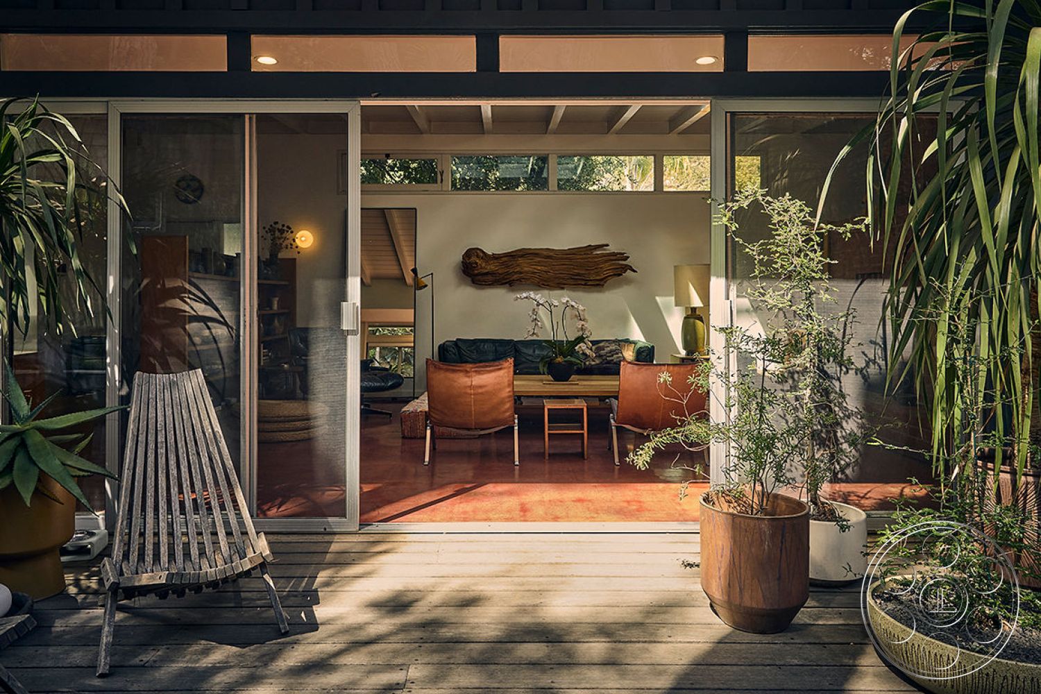 MCM 26 - minimalist design, glass sliding doors, warm ambient lighting, framed wall art, indoor outdoor flow, stylish coffee table, textured wall treatments, greenery accent, earth-toned color palette, studio-style layout, wooden lounge chair, exposed wood ceiling beams, interior hardwood floor, natural light interior, decorative floor lamp, potted indoor plants, contemporary lounge seating, modern wooden deck, organic shaped wooden artwork, rustic accent wall, open plan living space