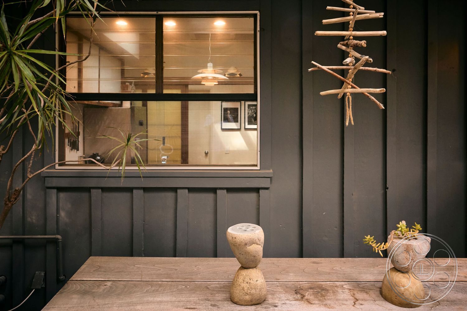 MCM 26 - modern aesthetic, natural wood dining table, contemporary design elements, soft lighting fixtures, structural beams, rustic outdoor setting, succulent plant arrangement, exterior wooden paneling, interior glass window with metal frame, minimalist garden decor, textured wall with horizontal panels, urban patio, natural stone decor pieces, decorative hanging art made from sticks, large glass opening for natural light