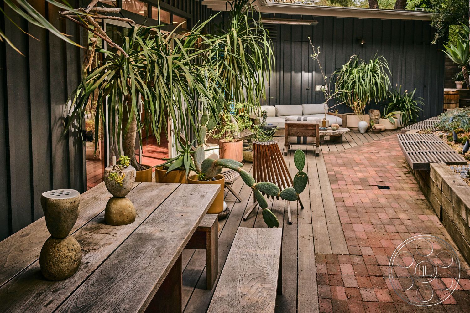 MCM 26 - textured wall panels, minimalist outdoor decor, lush garden setting, wooden patio flooring, modern outdoor seating area, exterior wooden dining table, tropical plant accents, private garden retreat, contemporary exterior design, brick pathway pavers, concrete outdoor planters, rustic wood beam structure, sunlit patio space