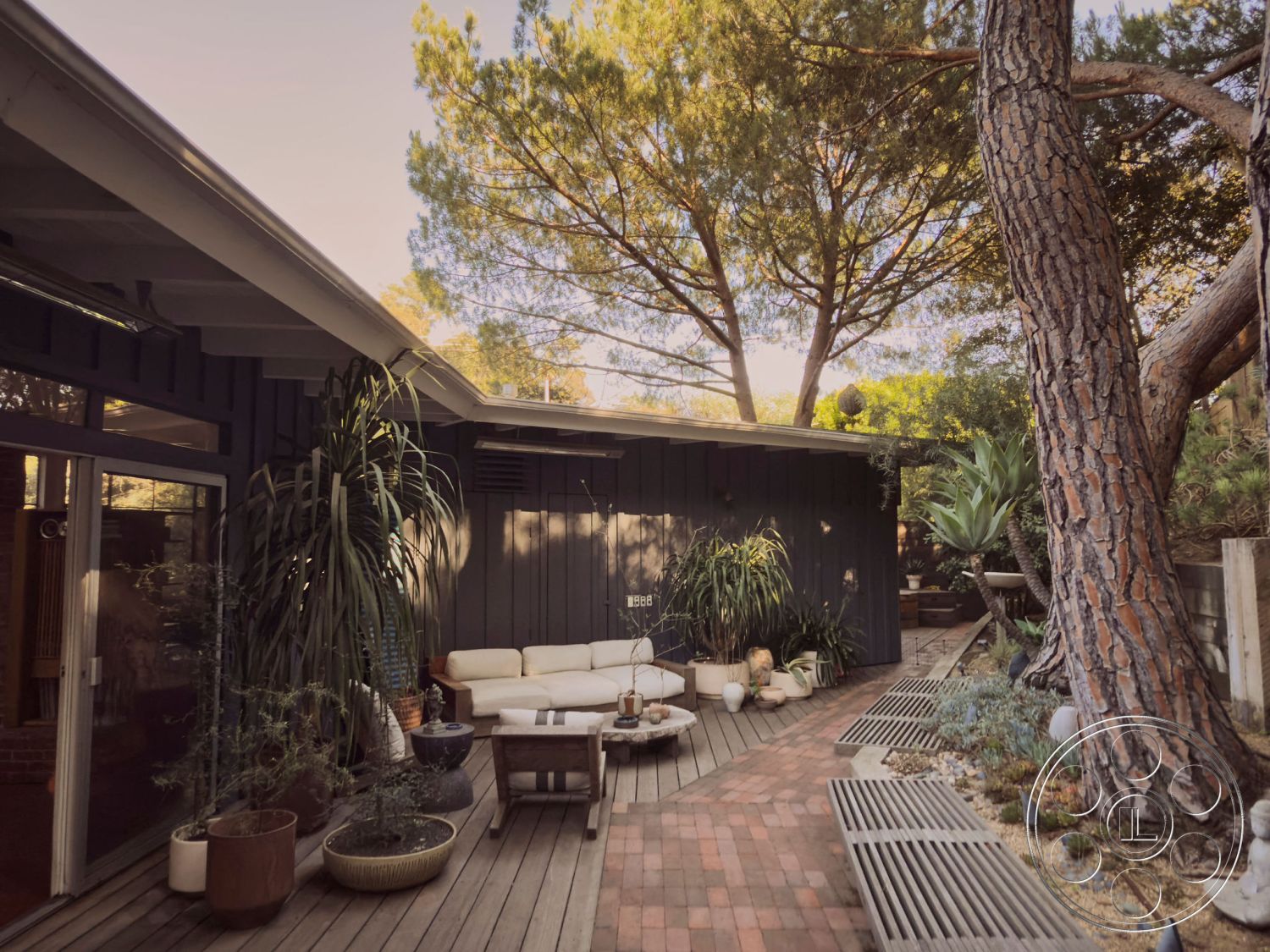 MCM 26 - exterior, landscaped garden, natural stone accents, contemporary design, glass sliding doors, surrounding trees, brick pathway, large potted plants, raised garden beds, sun-drenched patio, urban garden setting, modern outdoor seating area, wood paneling walls, organic shapes in landscaping, wooden deck floor