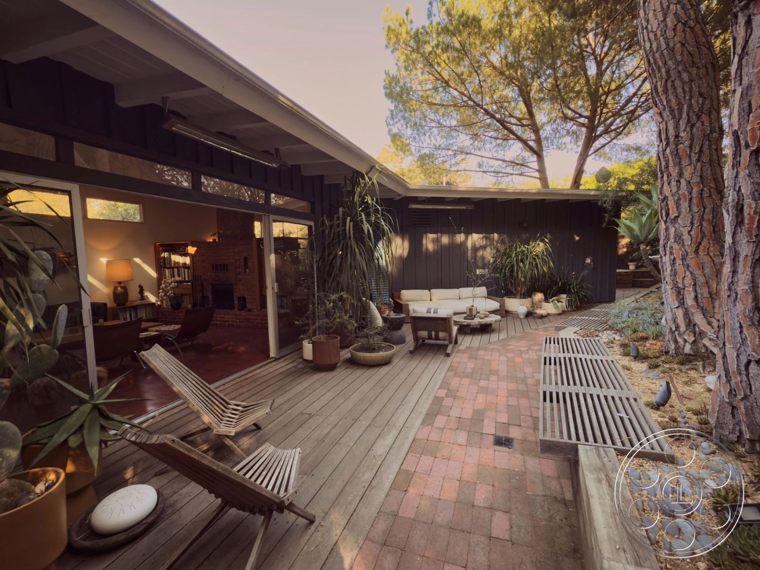 MCM 26 - sliding glass door, contemporary outdoor furniture, modern landscape design, open-air living space, decorative potted plants, minimalist outdoor decor, exposed brick fireplace wall, exterior wood deck, large windows with natural light, red brick paver pathway, cedar wood siding, sculptural stone features, pine tree shade, textured wood beam ceiling, organic garden elements