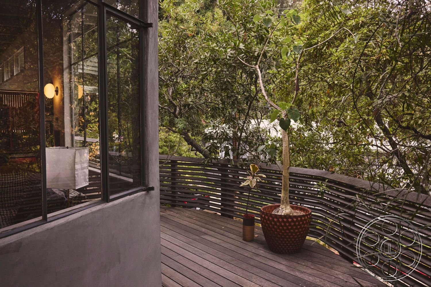 MCM 26 - natural wood accents, minimalist design elements, modern pendant lighting, city skyline view, contemporary outdoor space, floor-to-ceiling glass windows, surrounding lush greenery, integrated indoor-outdoor living, exterior wooden deck flooring, exposed concrete wall finish, curved wooden railing, large ceramic planter