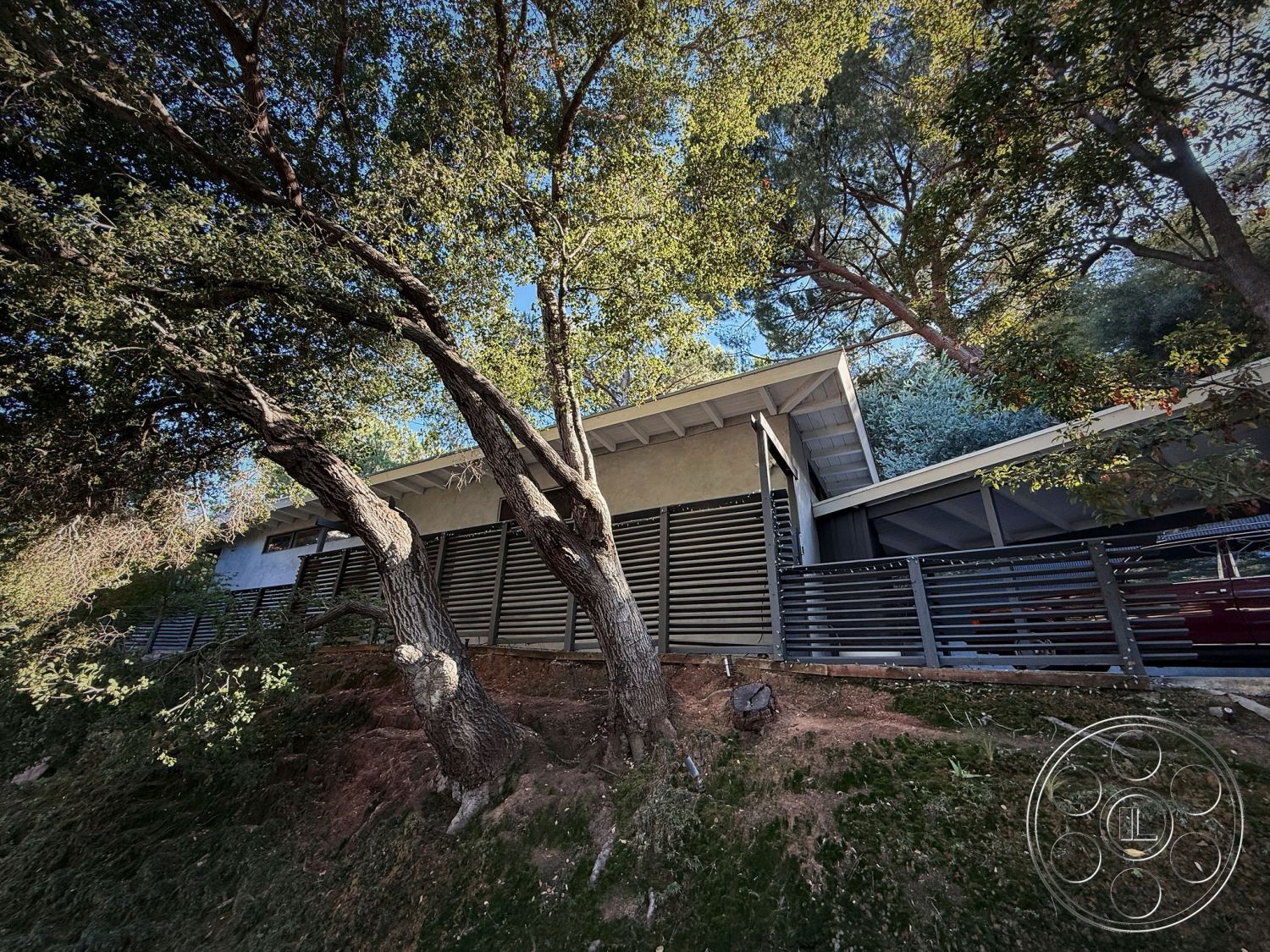MCM 26 - interior: floor-to-ceiling windows, interior: neutral color palette, exterior: modern residential design, exterior: concrete walls, exterior: wood paneling accents, exterior: metal railing, exterior: flat roof, exterior: large overhangs, exterior: landscaped hillside setting, exterior: surrounding oak trees, exterior: minimalistic architectural style, exterior: seamless integration with nature, interior: open concept layout, interior: natural light flooding in, interior: exposed wooden beams, interior: concrete flooring, interior: modern design elements, interior: sleek finishes