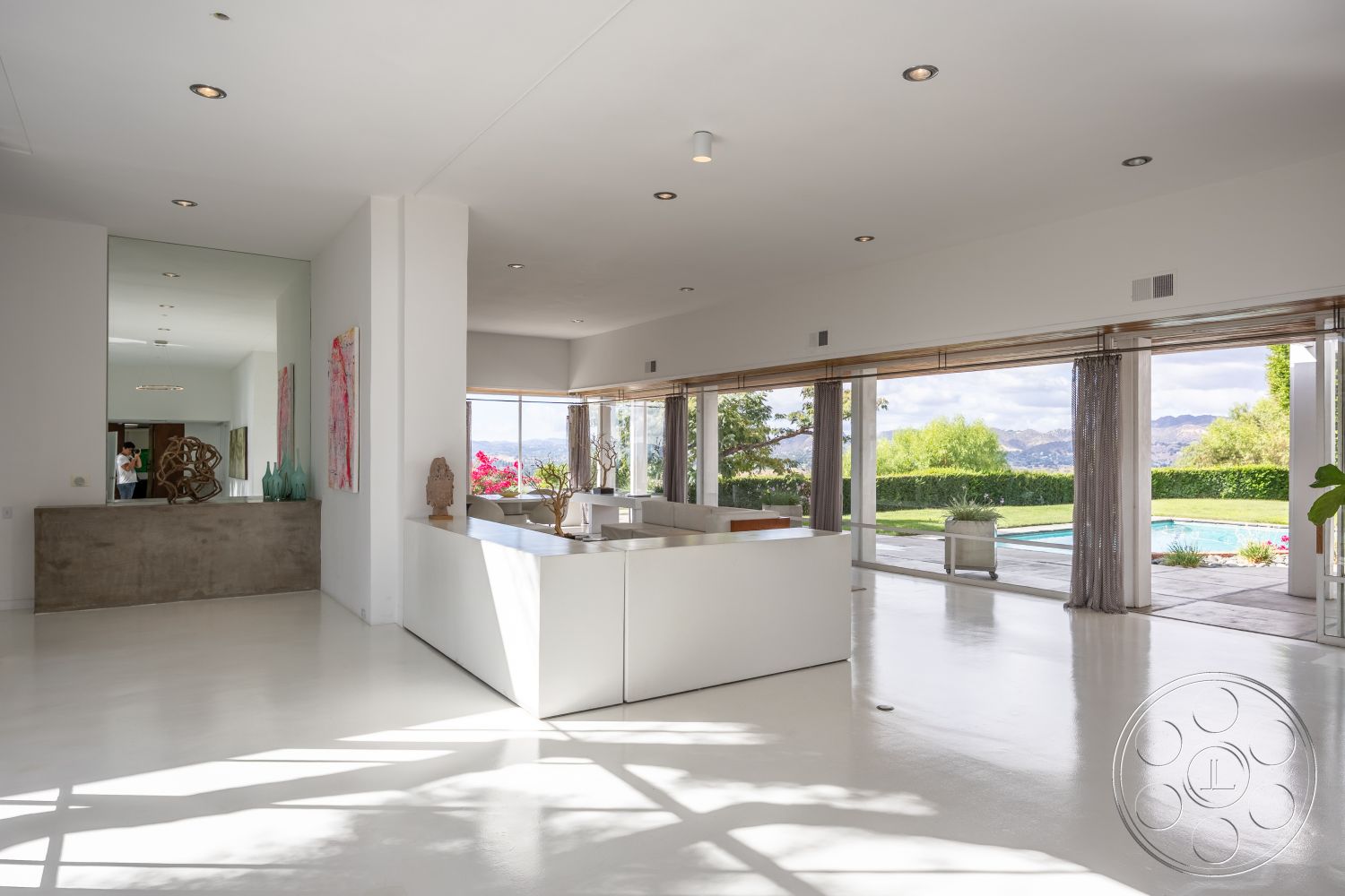 Sinatra House - polished concrete flooring, minimalist design elements, open concept layout, glass sliding doors, floor-to-ceiling windows, lush landscaping, city skyline view, textured wall decor, outdoor patio space, light-filled living area, rectangular pool view, contemporary art accents, white painted ceiling, concrete interior walls, modern kitchen with island