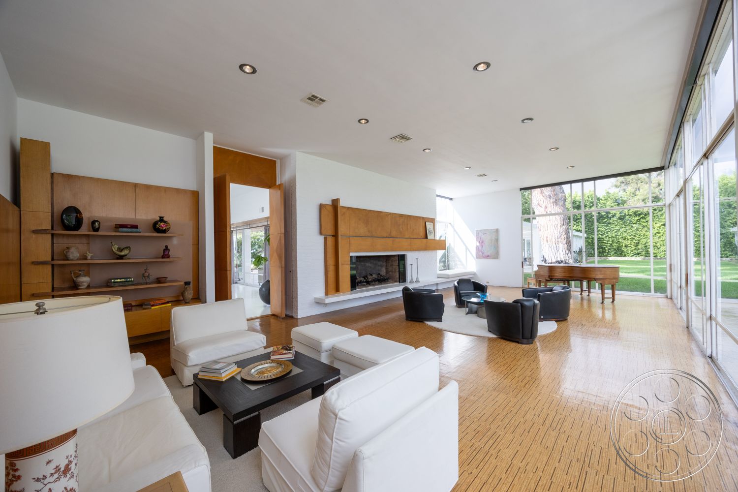 Sinatra House - exposed beam ceiling, open-concept living space, mid-century modern style, light wood accent wall, white painted walls, contemporary sectional sofa, clean lines architecture, built-in wooden shelves, natural light-filled room, rectangular room layout, interior bamboo flooring, modern fireplace with wood mantle, large floor-to-ceiling glass windows, minimalist black coffee table, elegant grand piano area, green hedge garden view