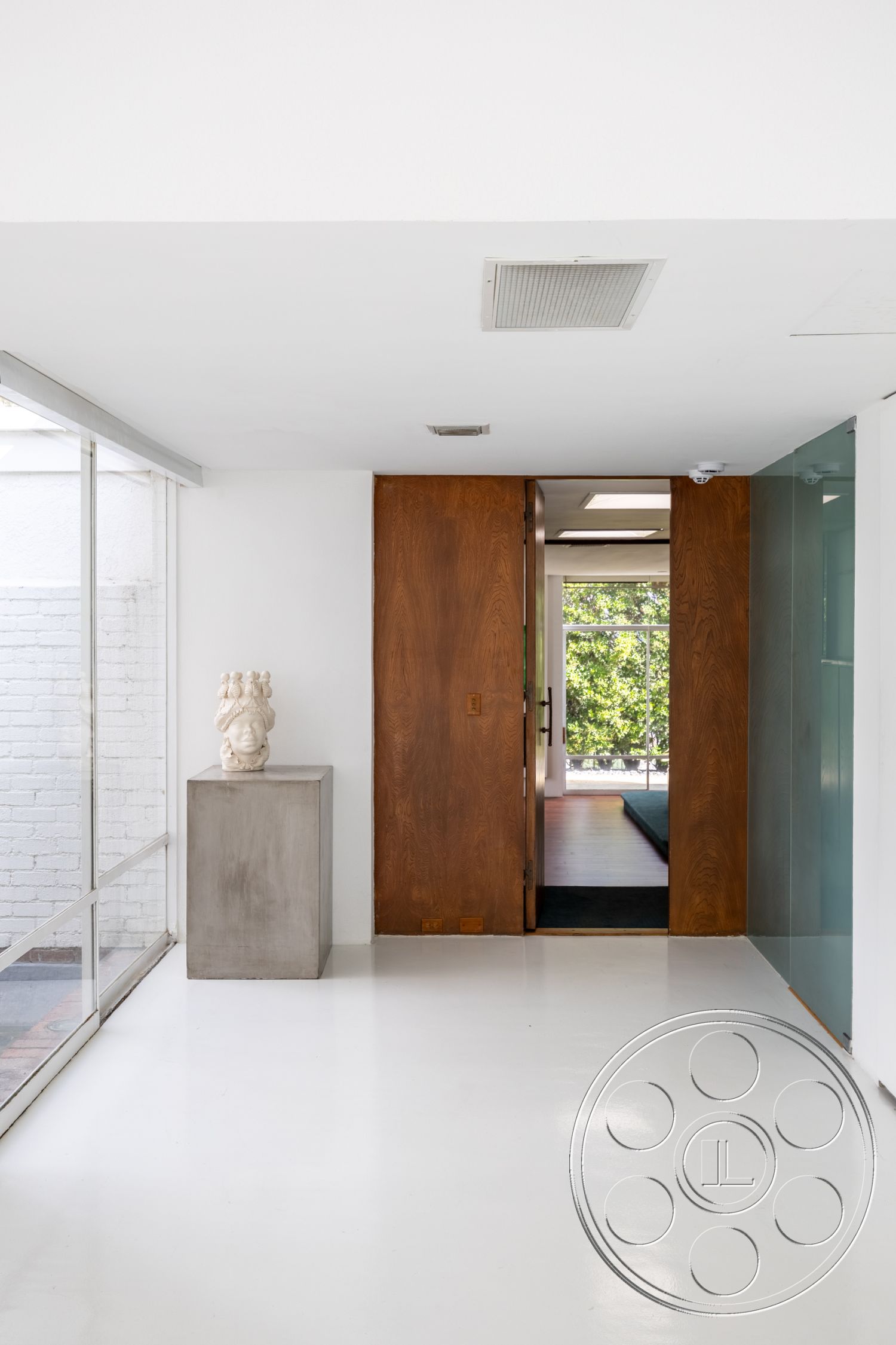 Sinatra House - contemporary style, open floor plan, polished concrete flooring, natural light from large windows, white painted walls, bright and airy ambiance, minimalist architectural design, interior entrance hallway, glass partition wall, walnut wood door, modern sculpture display, textured brick accent wall, steel and glass visual elements