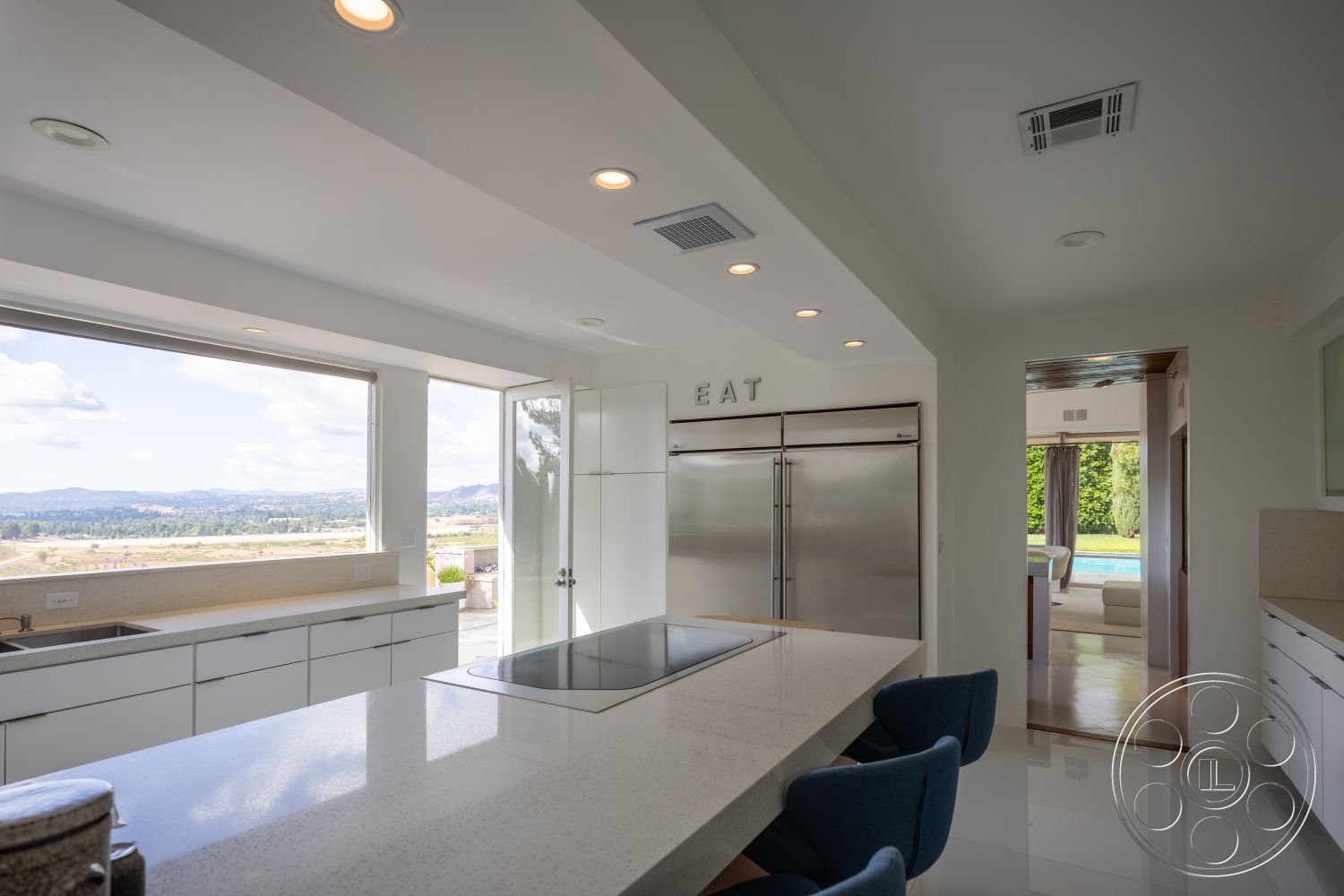 Sinatra House - neutral color palette, stainless steel appliances, minimalist design elements, white cabinetry, interior kitchen design, quartz kitchen countertops, open floor plan kitchen, high ceilings with recessed lighting, ceramic tile kitchen flooring, wraparound kitchen island, large glass windows with mountain view, contemporary kitchen layout, sliding glass door to outdoor pool area