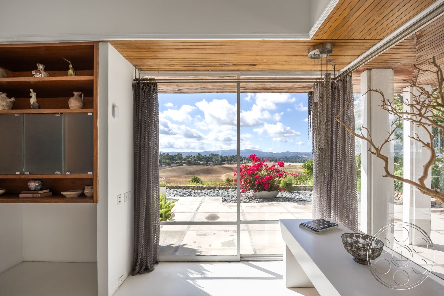 Sinatra House - neutral color palette, natural light, minimalist design, large glass sliding doors, open layout, landscape view, contemporary furnishings, eco-friendly materials, wooden shelving units, exposed wood ceiling beams, white painted walls, concrete floor slab, modern home office, decorative ceramic accents, textured curtain treatment, flowering potted plants, stylish accent table, views of rolling hills