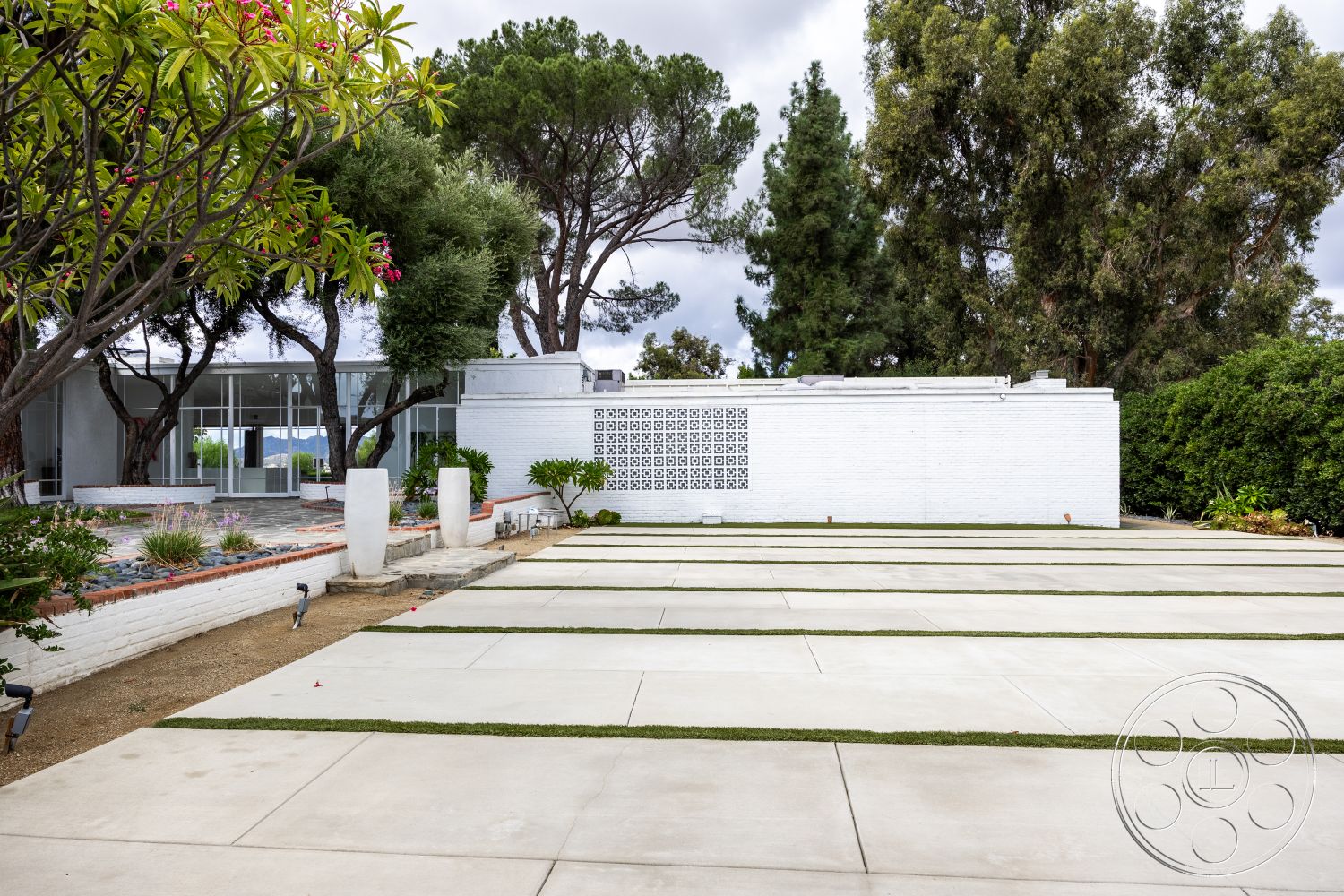 Sinatra House - natural stone accents, planted greenery, modern residential architecture, landscaped garden area, exterior concrete driveway, minimalist garden design, surrounding tree canopy, horizontal concrete slabs, urban outdoor setting, decorative concrete block wall, white painted brick walls, rectangular landscaping beds, symmetrical outdoor layout, open space with vegetation, concrete pathway with grass strips