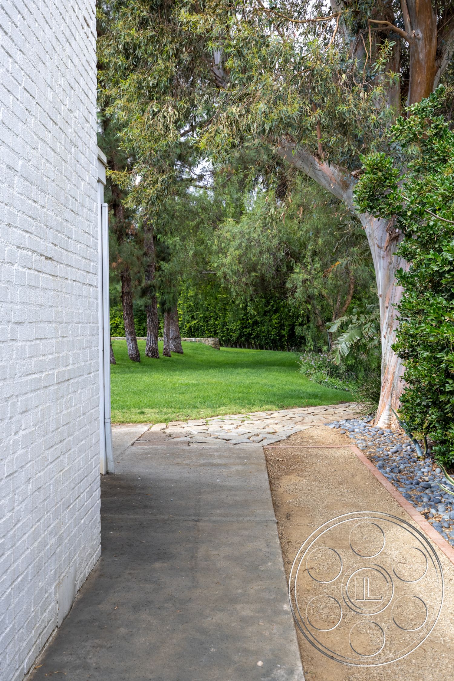 Sinatra House - exterior, landscaped garden, mature trees, exposed brick wall, stone pathway, lush green lawn, concrete walkway, natural stone pavers, outdoor path, flat concrete surface, gravel border, dense shrubbery