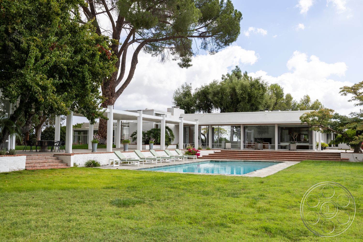 Sinatra House - landscaped garden, exposed wooden beams, rectangular swimming pool, surrounding trees, concrete pool deck, natural stone steps, white painted exterior walls, suburban backyard setting, exterior pool area, brick stepping stones, sloped green lawn, glazed patio doors, modern outdoor lounge furniture, covered patio structure, screened outdoor dining area