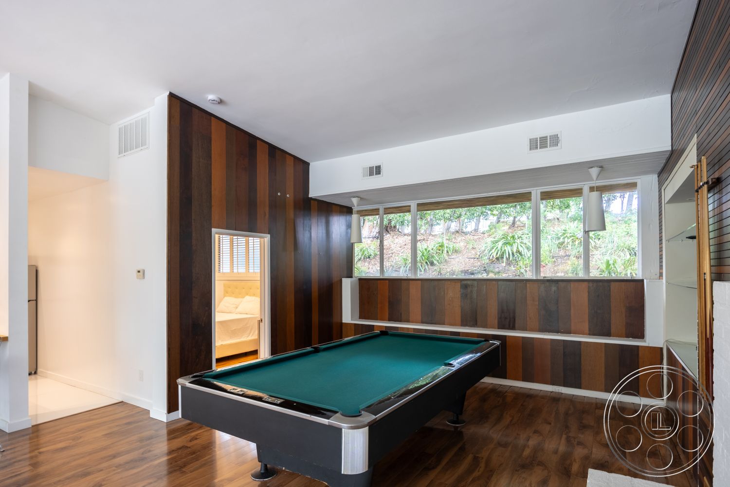 Sinatra House - modern pendant lighting, floor-to-ceiling windows, open concept living space, recessed ceiling lights, minimalist interior design, neutral painted walls, suburban home interior, exposed wood paneling wall, hardwood game room floors, game room with pool table, landscape view through windows