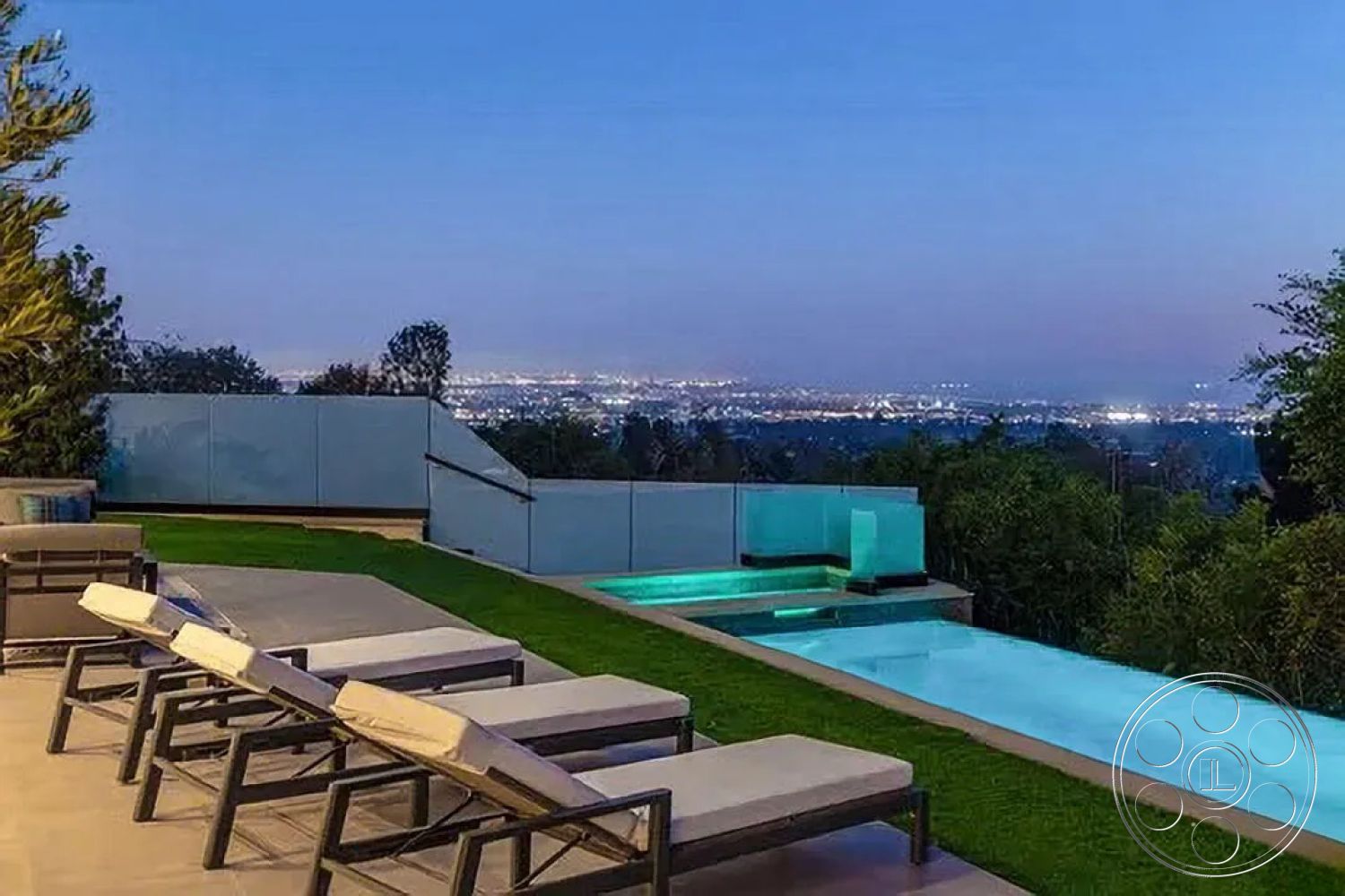 Modern 512 - exterior, landscaped garden, glass railing, infinity pool, modern lounge chairs, luxury outdoor living space, concrete pool edge, stone pavers patio, synthetic grass lawn, nighttime city skyline view