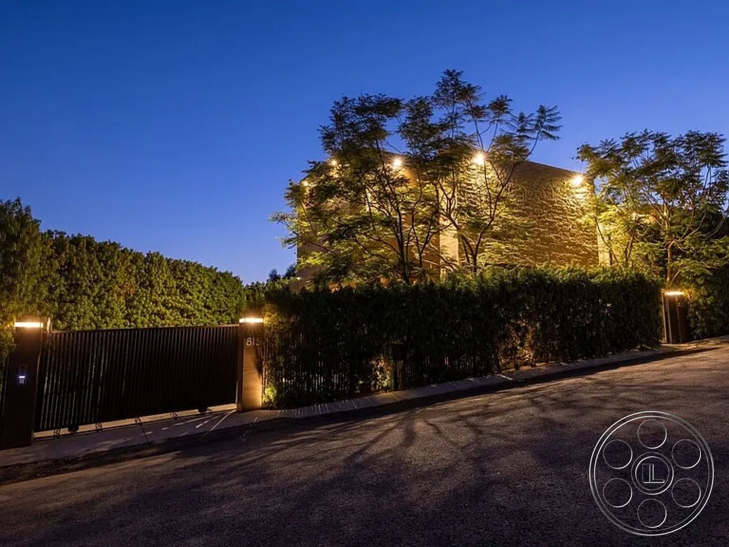 Modern 512 - minimalist design elements, modern architectural style, sloped driveway, privacy landscaping, pathway lighting fixtures, metal gate entrance, contemporary home facade, suburban neighborhood setting, exterior wall cladding stone, landscaped garden with trees, dark wood fencing, nighttime ambiance lighting, textured stone exterior, paved driveway surface